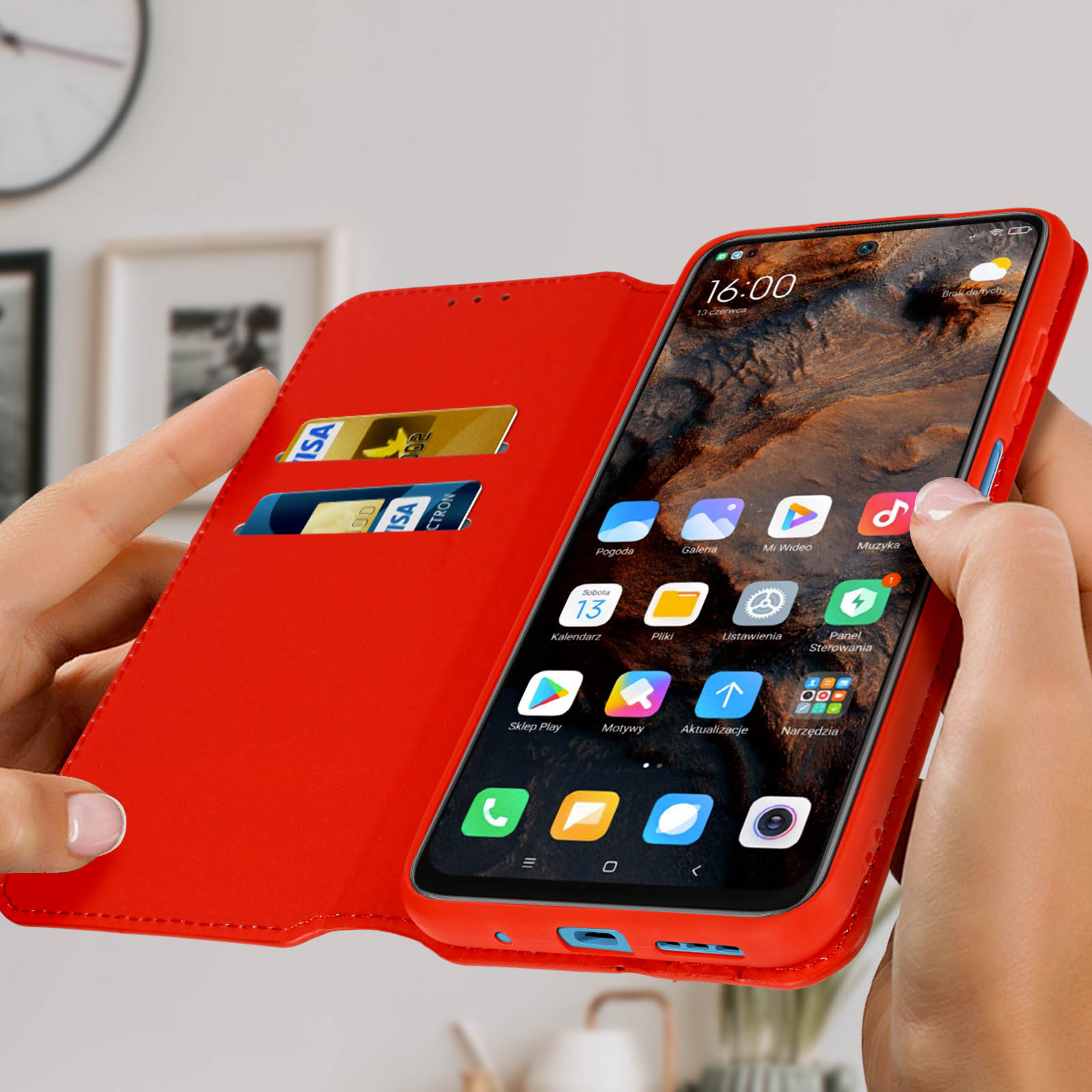Una custodia rossa per telefono è aperta, mostrando un telefono con icone di app. Due carte di credito sono nello slot sinistro.