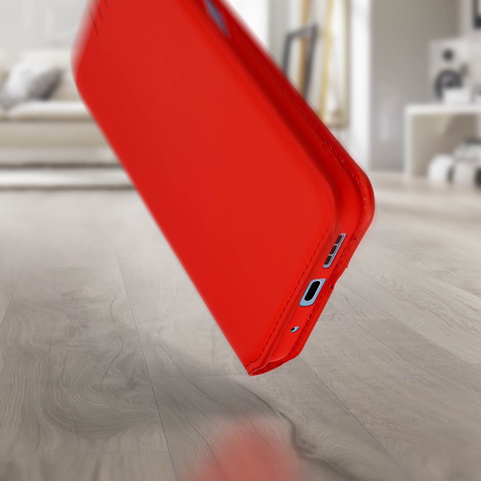 Custodia rossa per telefono che cade, con la parte inferiore rivolta verso lo spettatore. Porta di ricarica blu visibile.