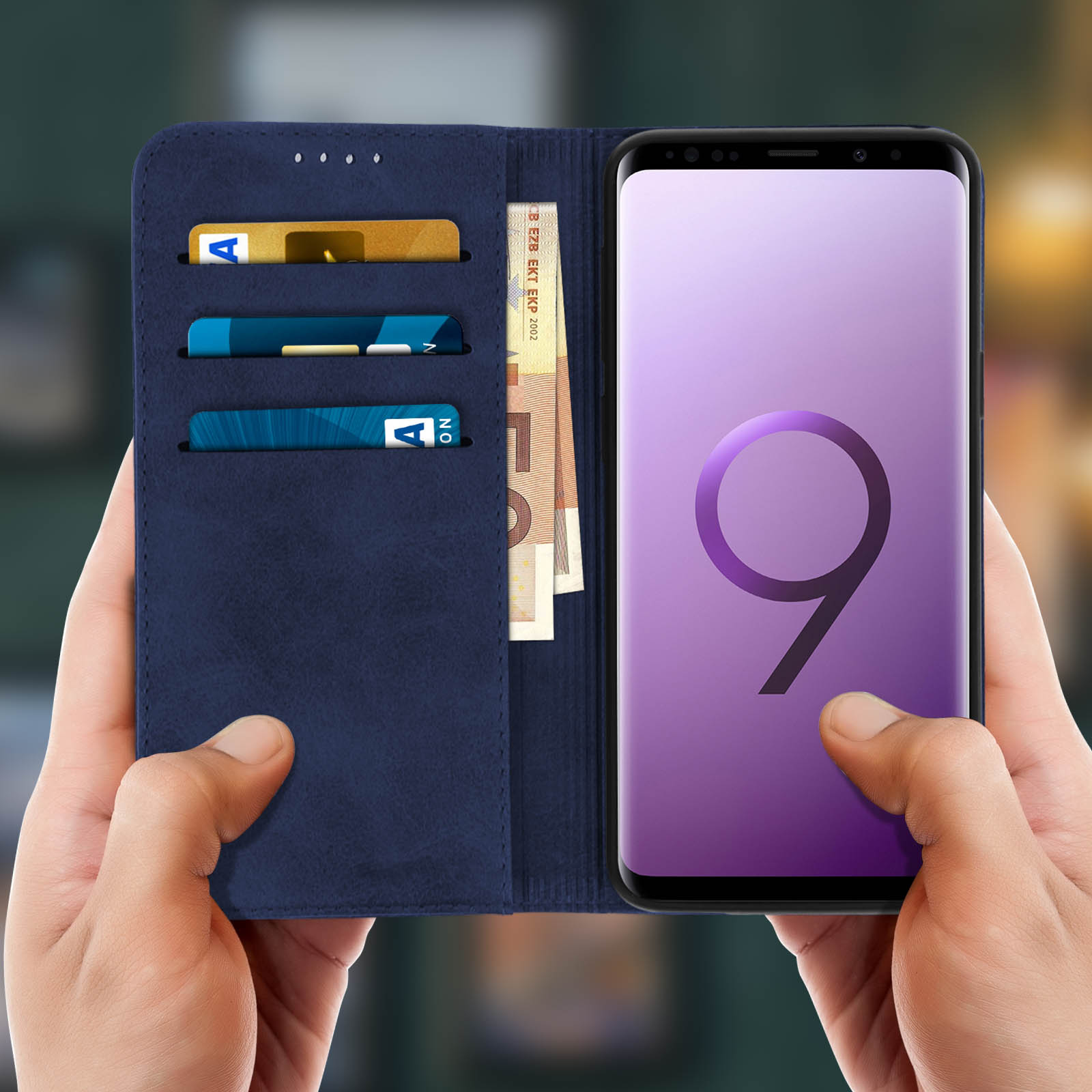 Mani che tengono una custodia per telefono blu navy con carte e valuta. Lo schermo del telefono ha un '9'.