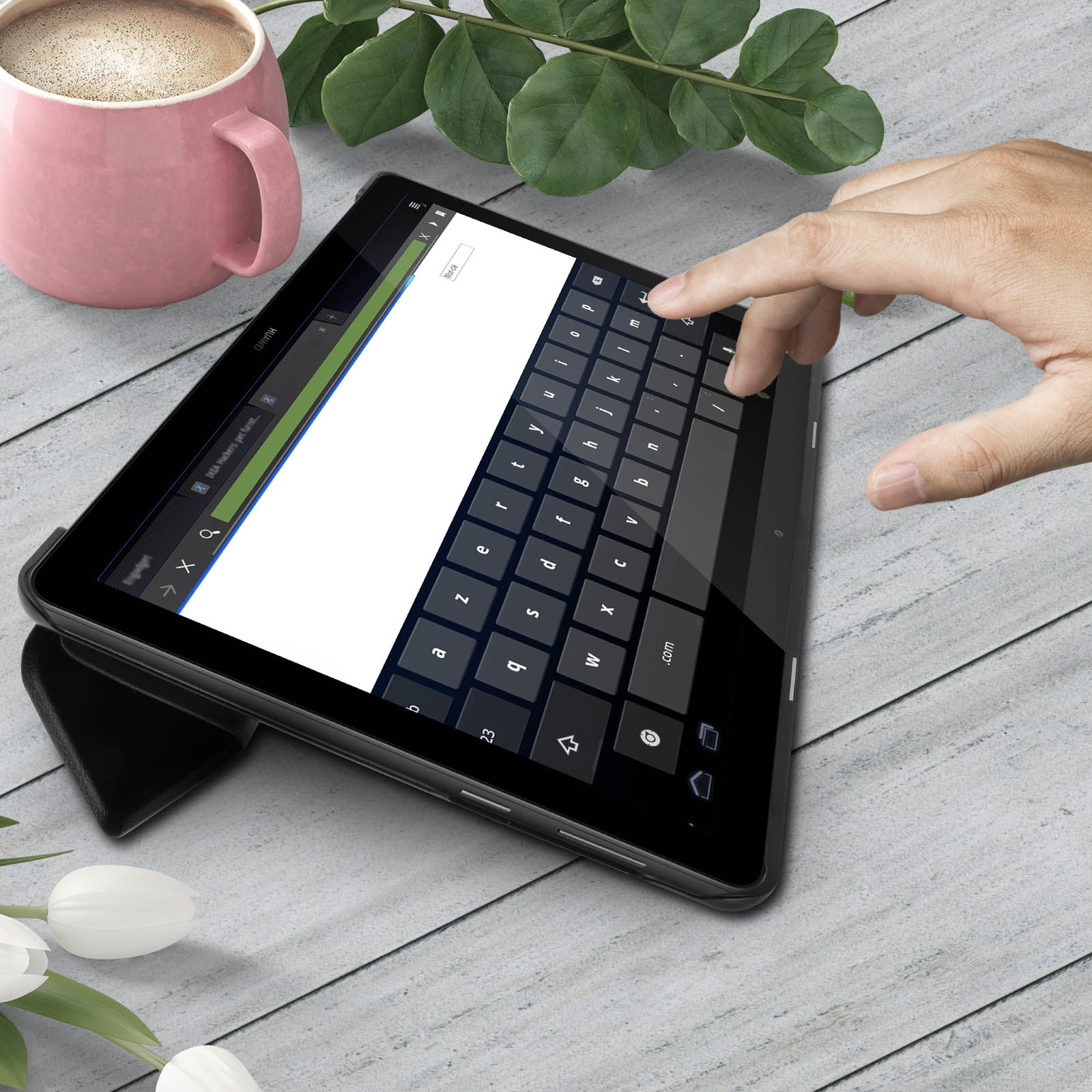 Un tablet con tastiera, una tazza e fiori su un tavolo di legno.