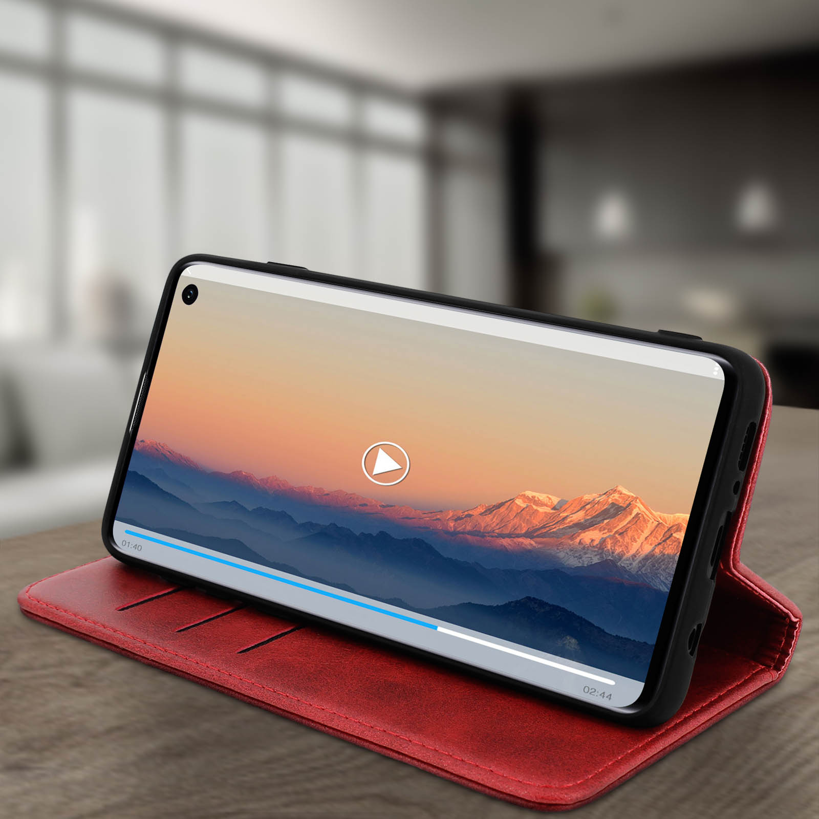 Telefono in una custodia rossa, che mostra un video di un paesaggio montano.