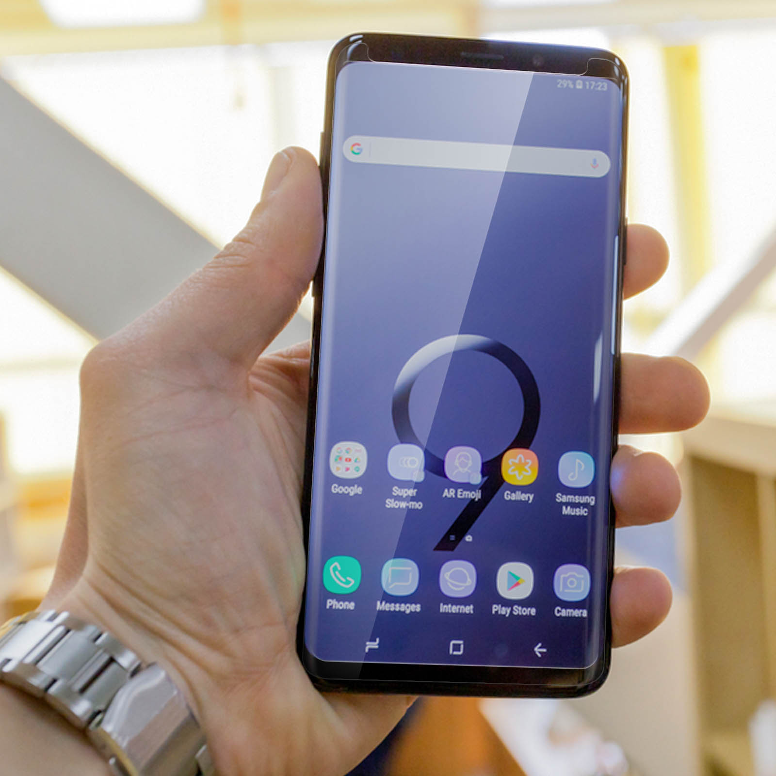 Mano che tiene il telefono mostrando le icone della schermata iniziale. Sfondo sfocato.
