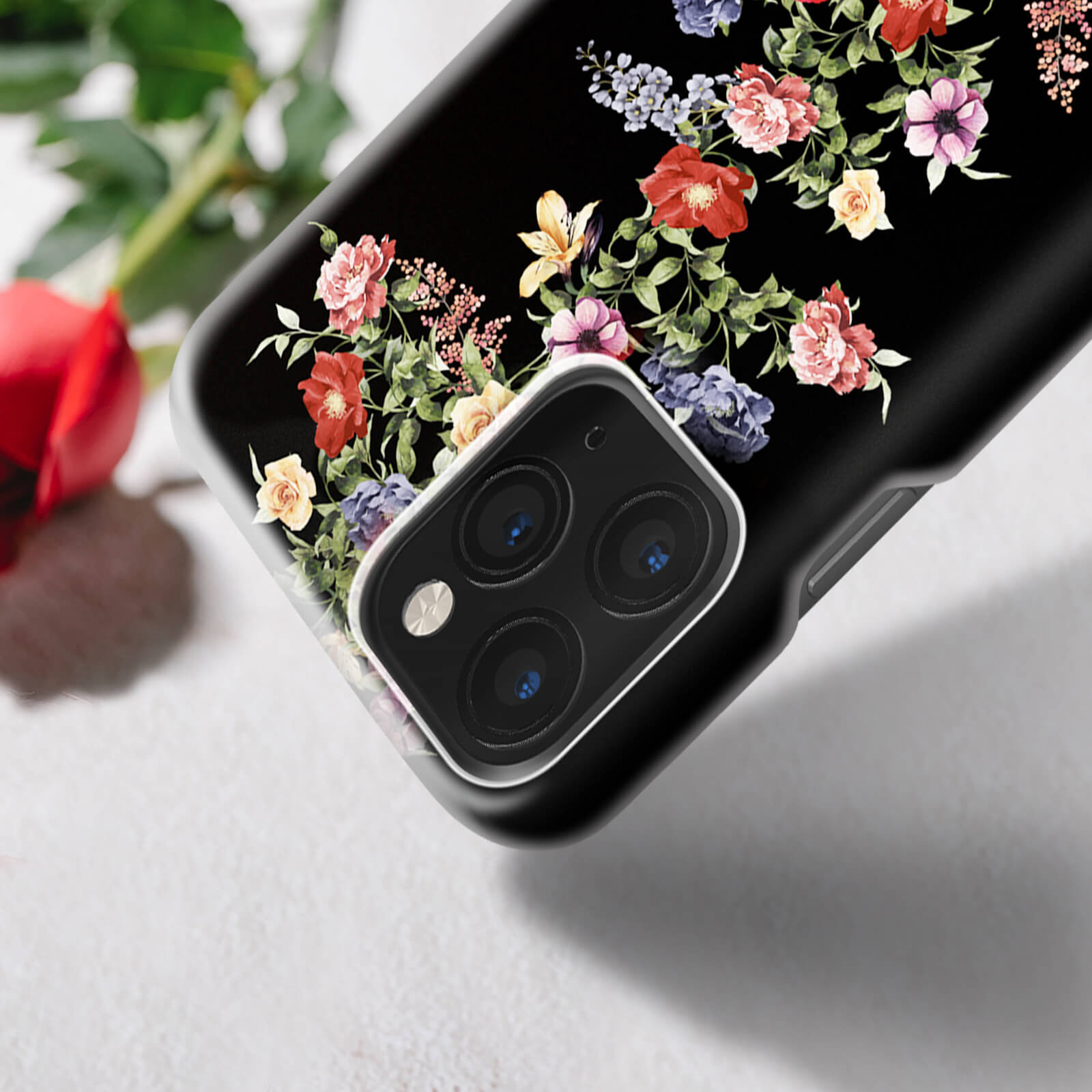 Eine schwarze Handyhülle mit Blumendesign, die die Kameralinsen zeigt.