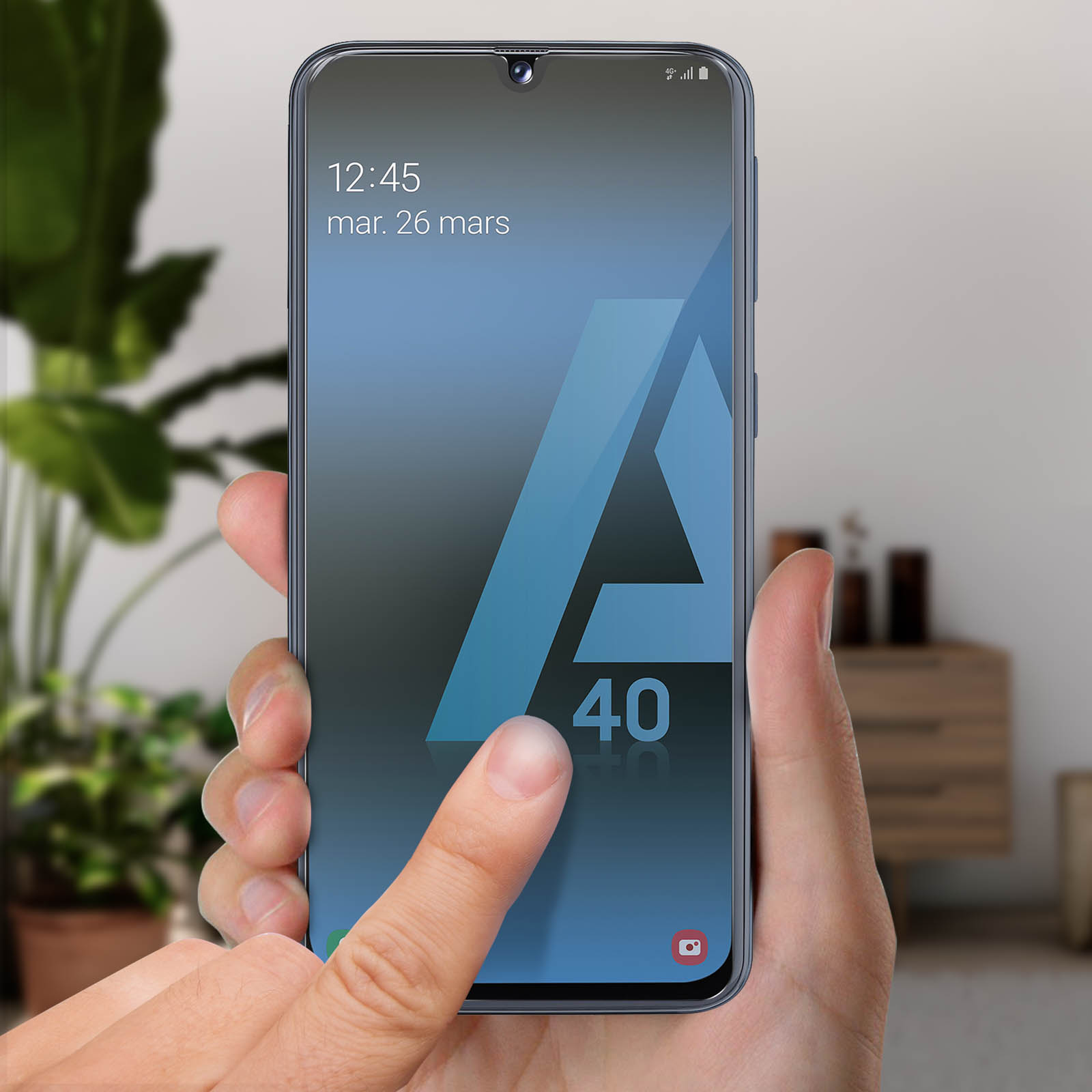 La mano di una persona tocca lo schermo di uno smartphone che mostra l'ora e un logo. Il telefono ha una cornice blu.