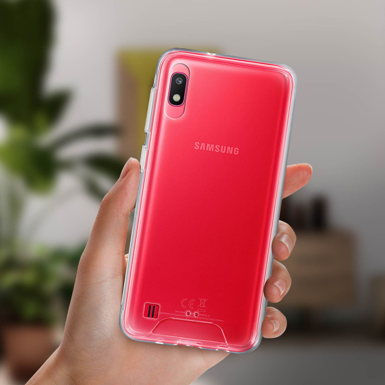 Main tenant un téléphone Samsung rouge dans une coque transparente.