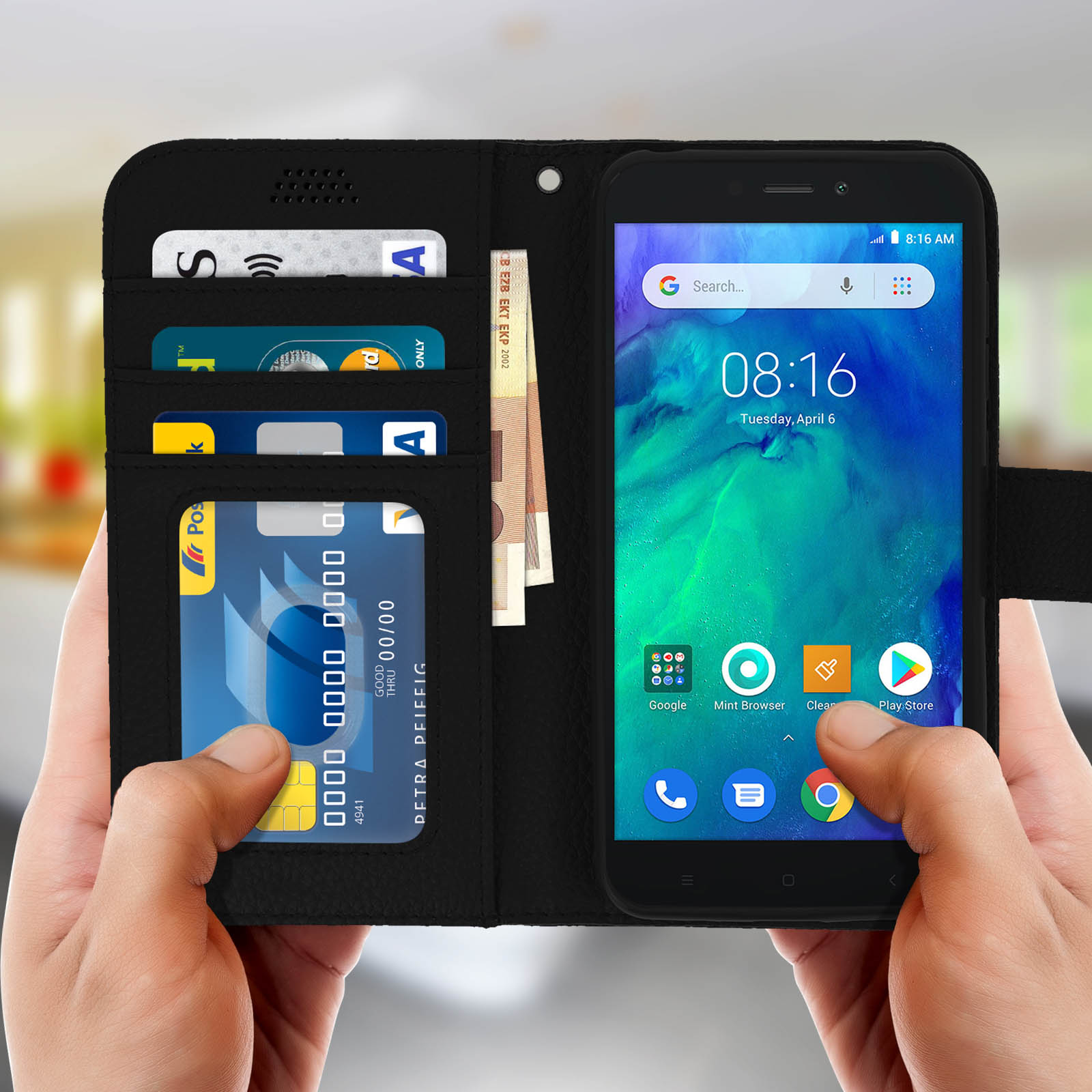 Una custodia nera per telefono con denaro e carte all'interno. Un telefono mostra l'ora e le app. Mani.