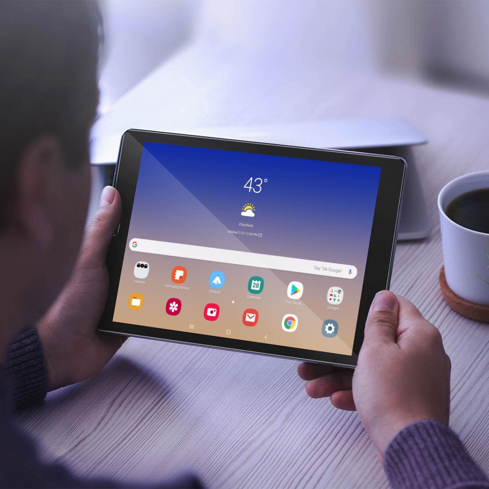 Une personne tenant une tablette. La tablette affiche une application météo et des icônes.