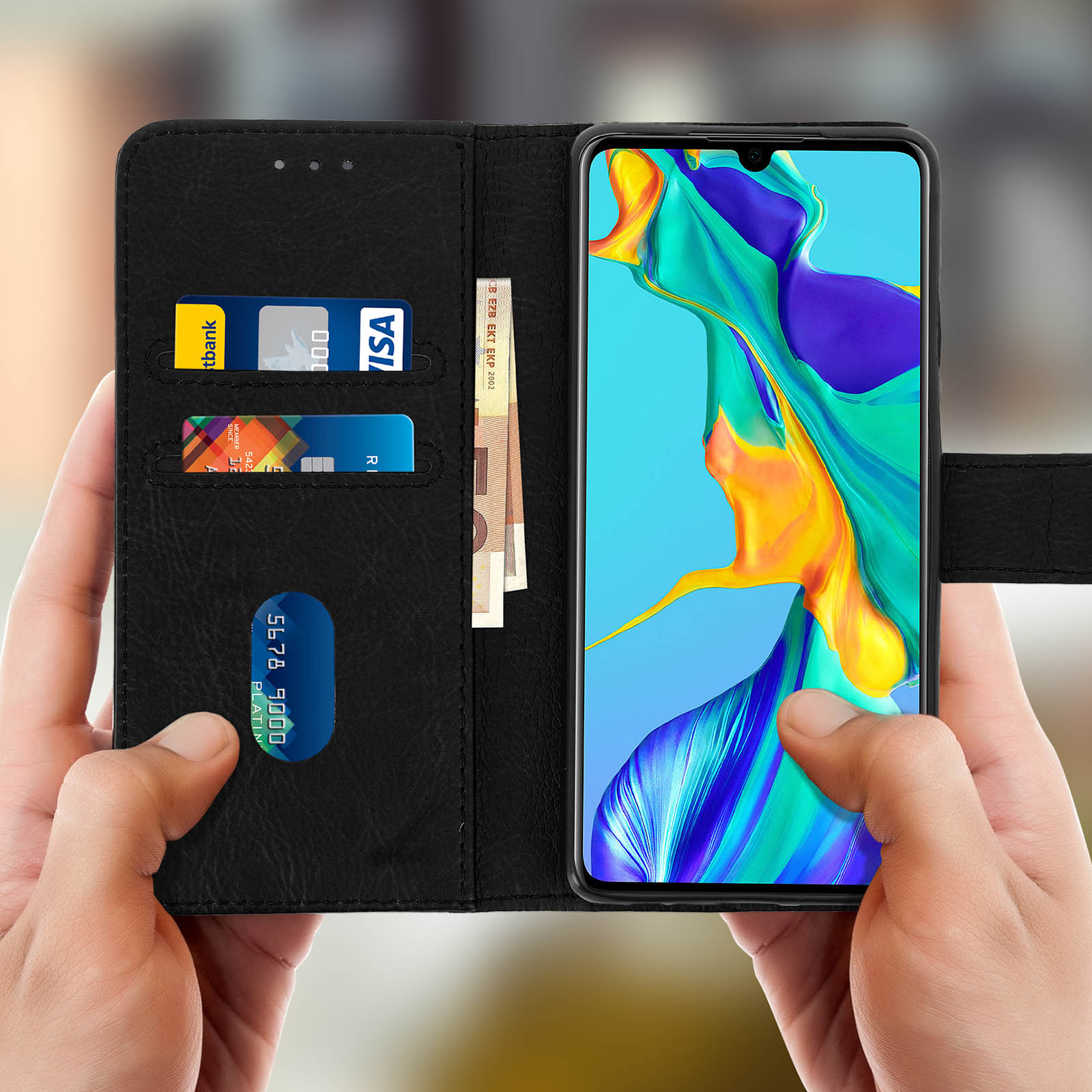 Le mani tengono aperta una custodia nera per telefono, mostrando carte di credito e contanti. Il telefono mostra grafiche colorate.