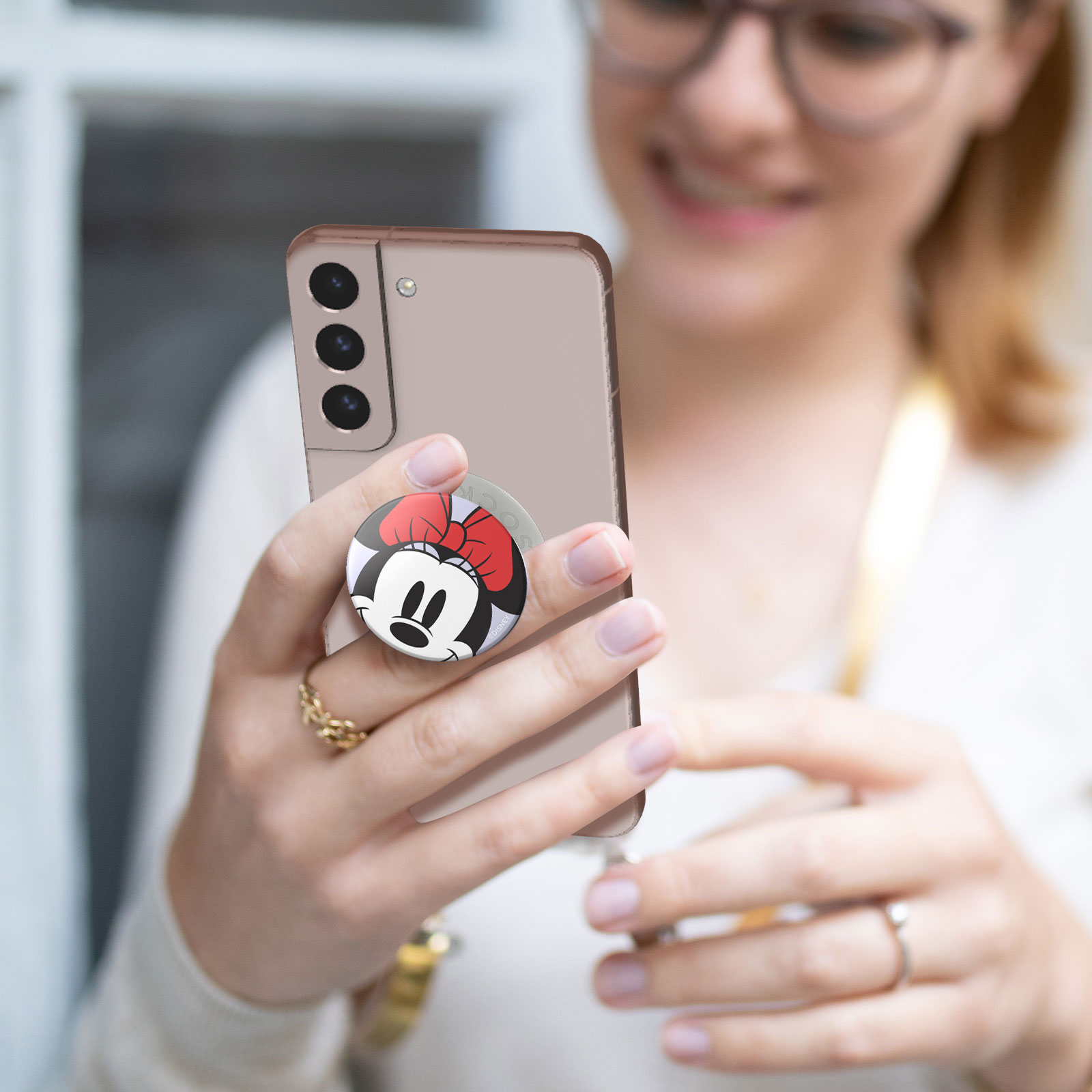 Eine Person hält ein Telefon mit einem Minnie Mouse Pop-Socket darauf.