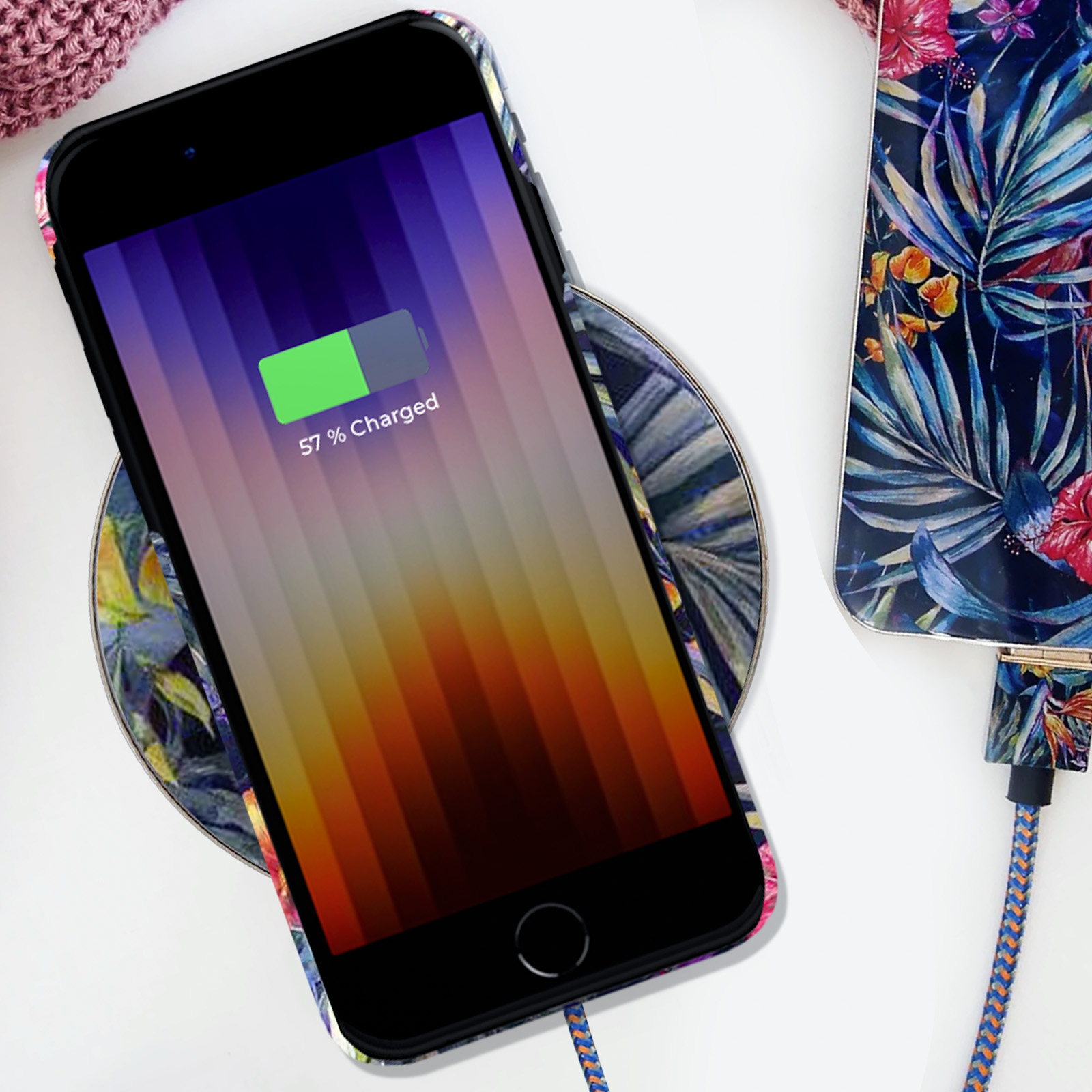 Un telefono si sta caricando su un caricatore wireless. Il telefono è in una custodia floreale, che mostra il 57% di carica.