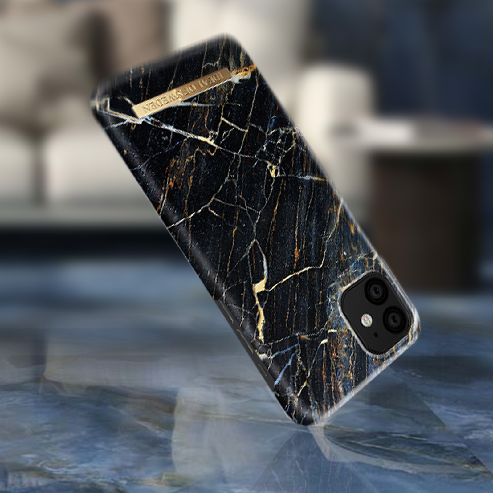 Altın detaylı mermer telefon kılıfı. Kılıf, hafif açılı, bulanık bir yüzeyde.