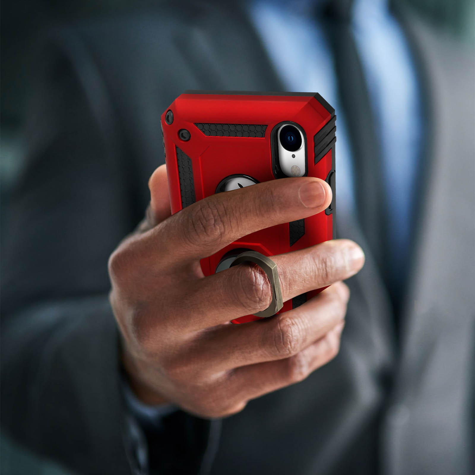 Una persona tiene in mano un telefono con una custodia rossa e un portanello. Sfondo sfocato di un abito.