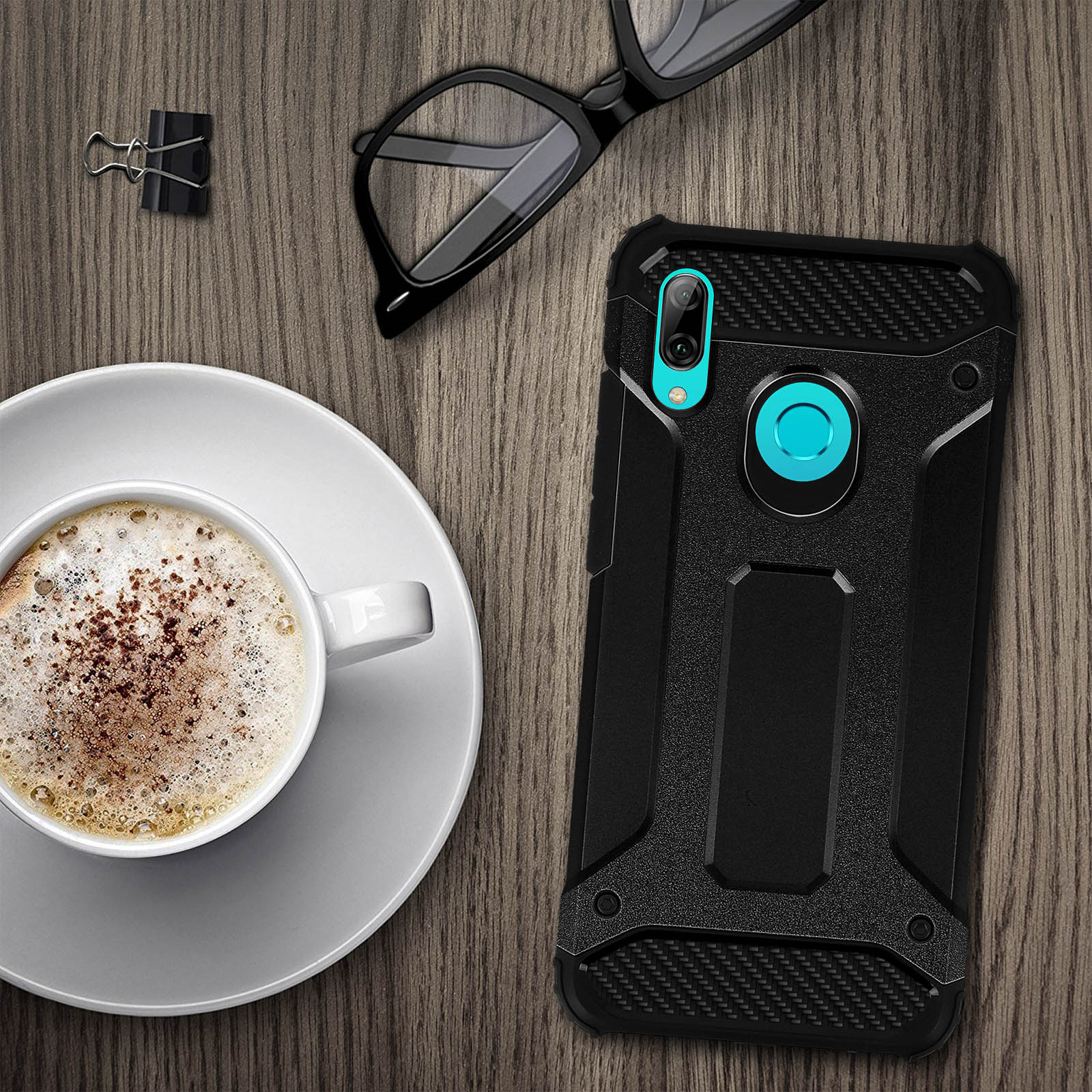 Telefon und Hülle auf dem Tisch, in der Nähe von Kaffee und Brille. Hülle ist schwarz, Bildschirm an.