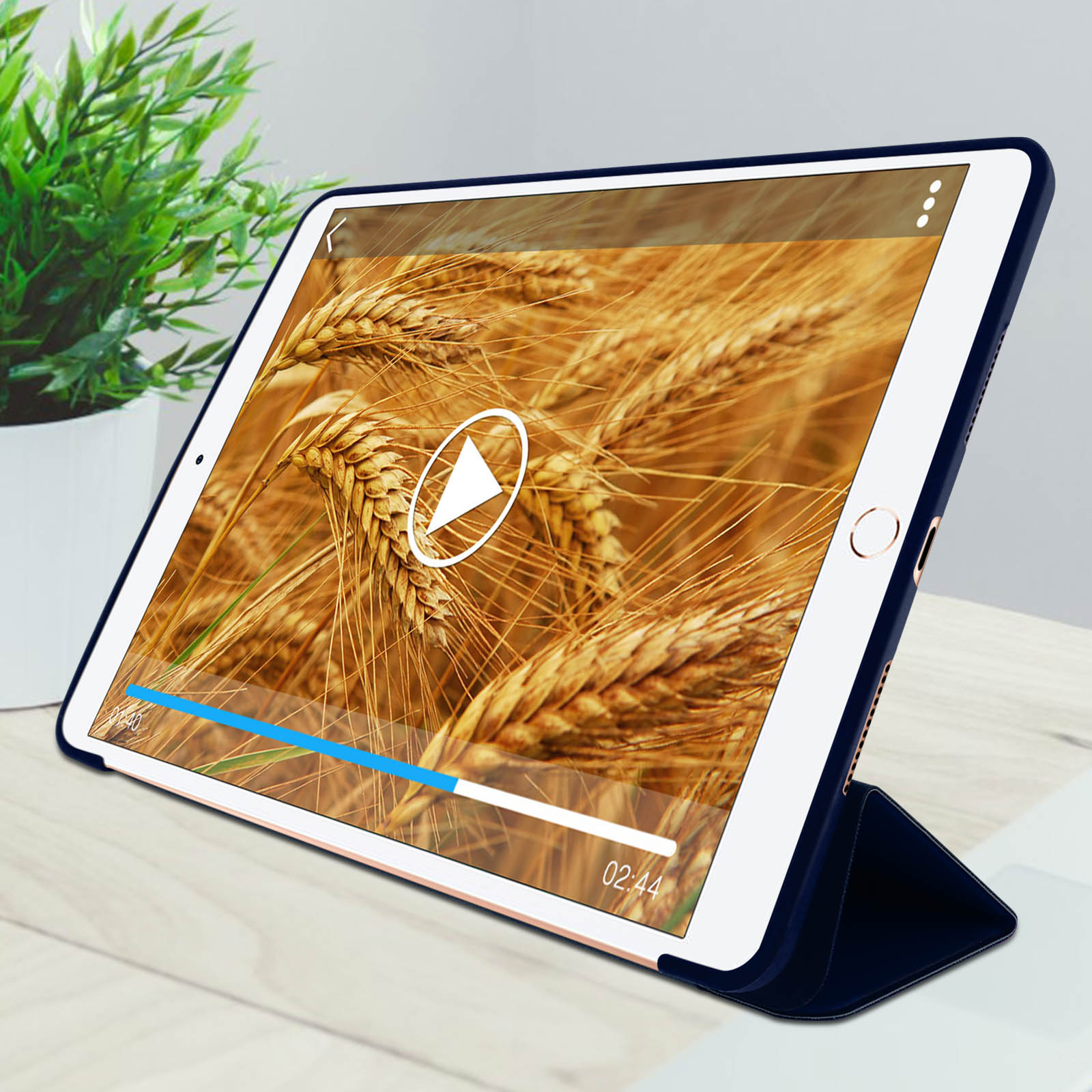 Tablet che mostra un video di grano. È all'interno di una custodia blu scuro, su un tavolo di legno.