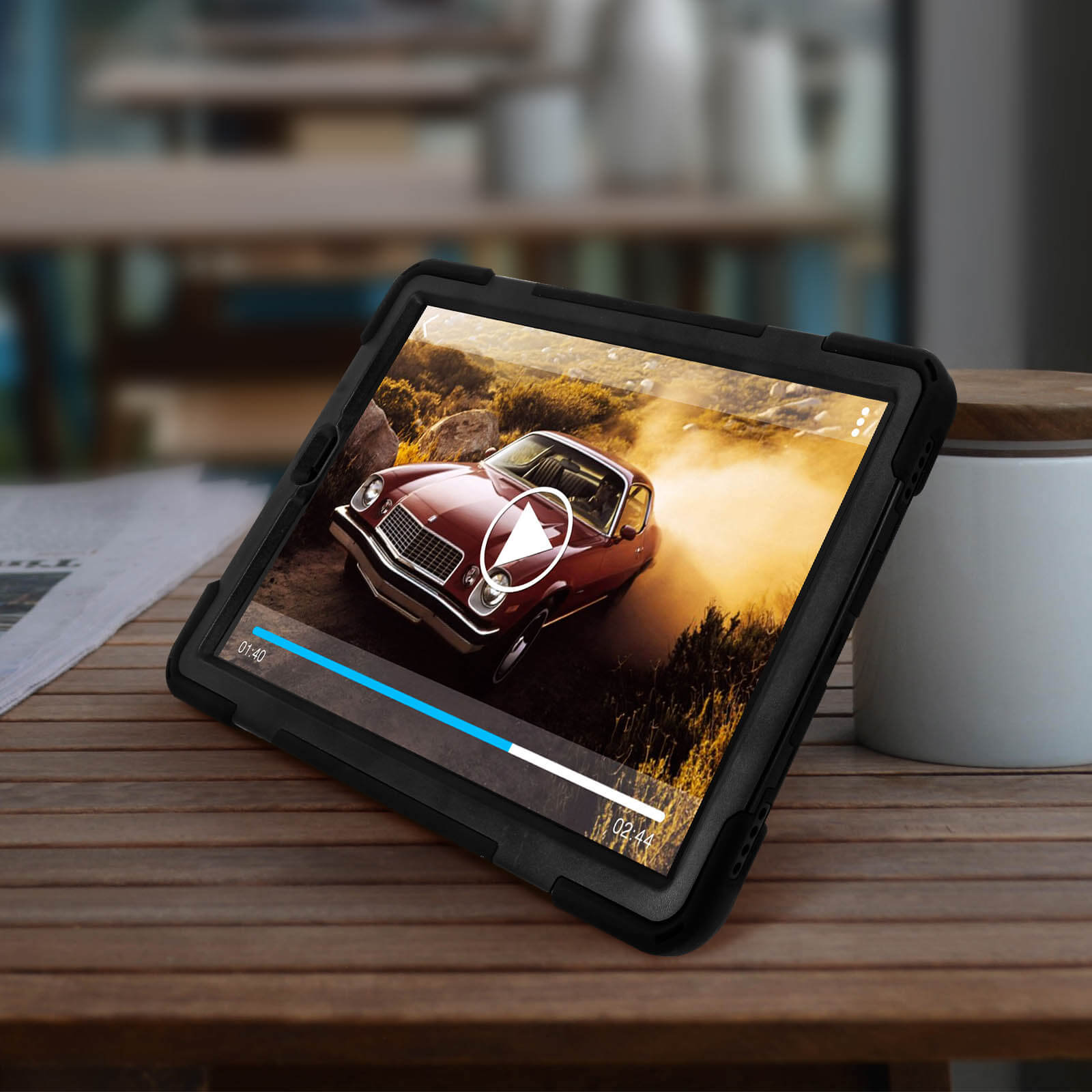 Ein Tablet mit schwarzem Gehäuse zeigt ein Autovideo, das auf einem Holztisch liegt.