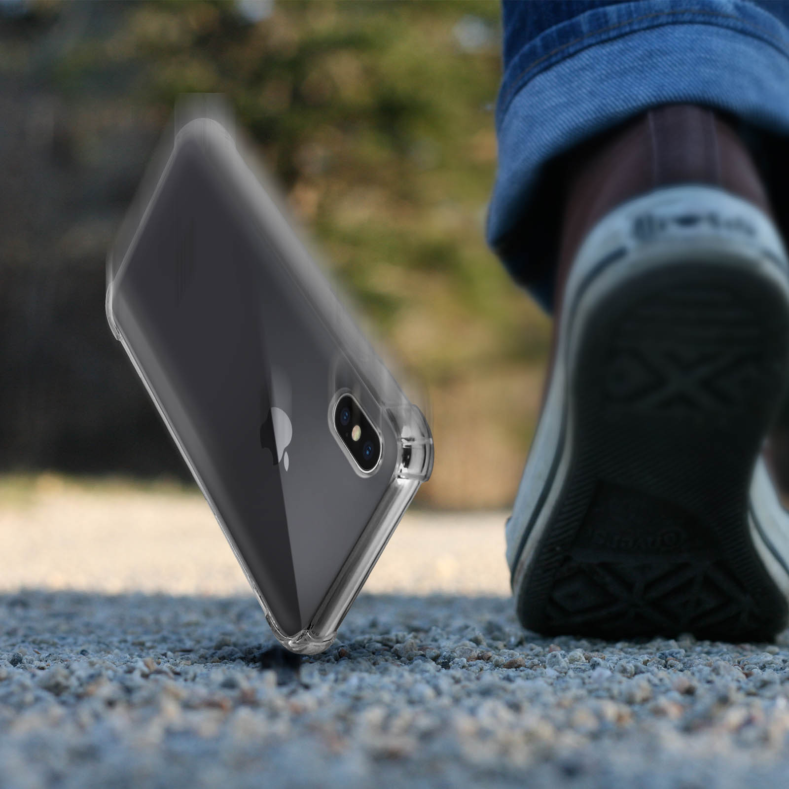 Custodia trasparente per telefono che cade. Le gambe e le scarpe di una persona sono sullo sfondo.