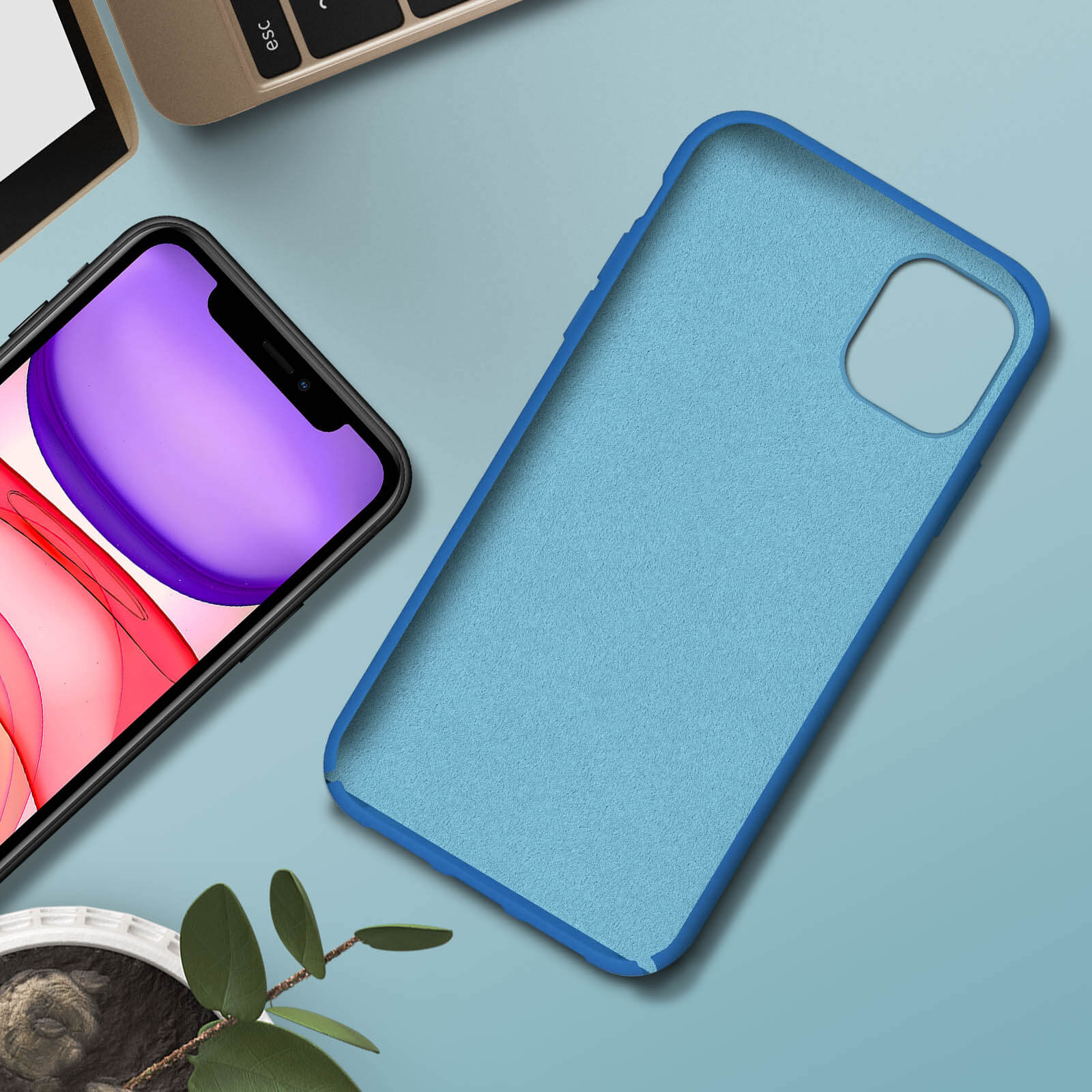 Coque de téléphone bleue avec un téléphone à l'intérieur. Plante verte et clavier en arrière-plan.