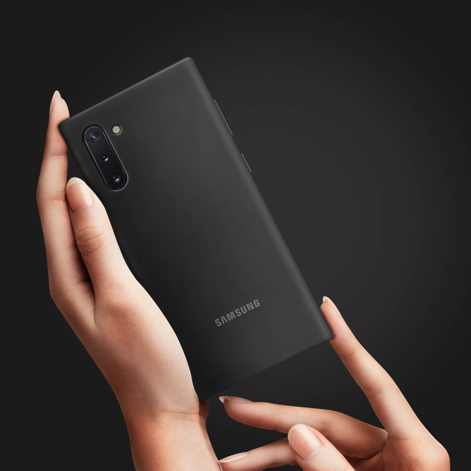 Un teléfono negro se sostiene en manos. Fondo oscuro. Logotipo de Samsung visible.