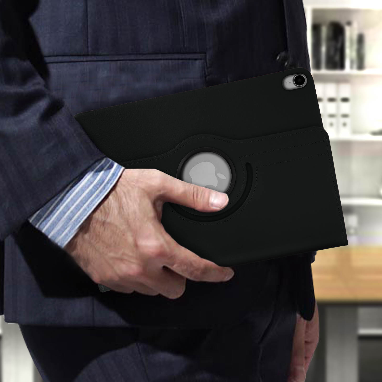 Uomo che tiene un tablet nero in una custodia di pelle. Indossa un abito in un ambiente d'ufficio.