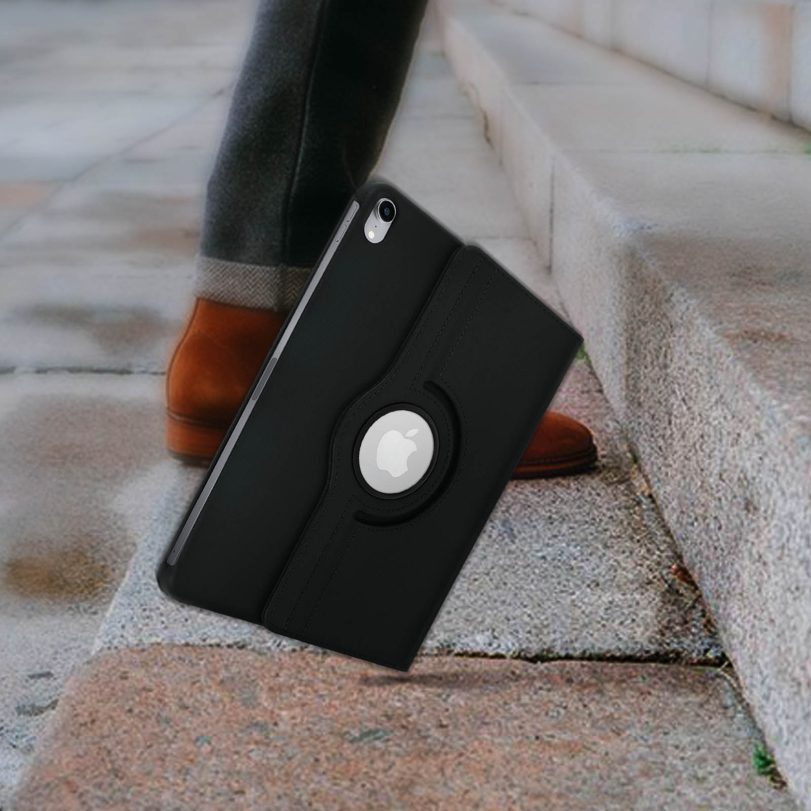 Custodia iPad nera con logo Apple bianco, parzialmente aperta, su gradini con gambe e scarpe di una persona.