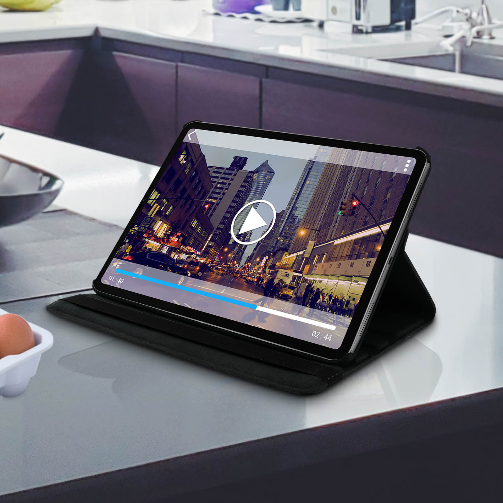 Tablet in una custodia nera. Lo schermo mostra un video, su un piano cucina.