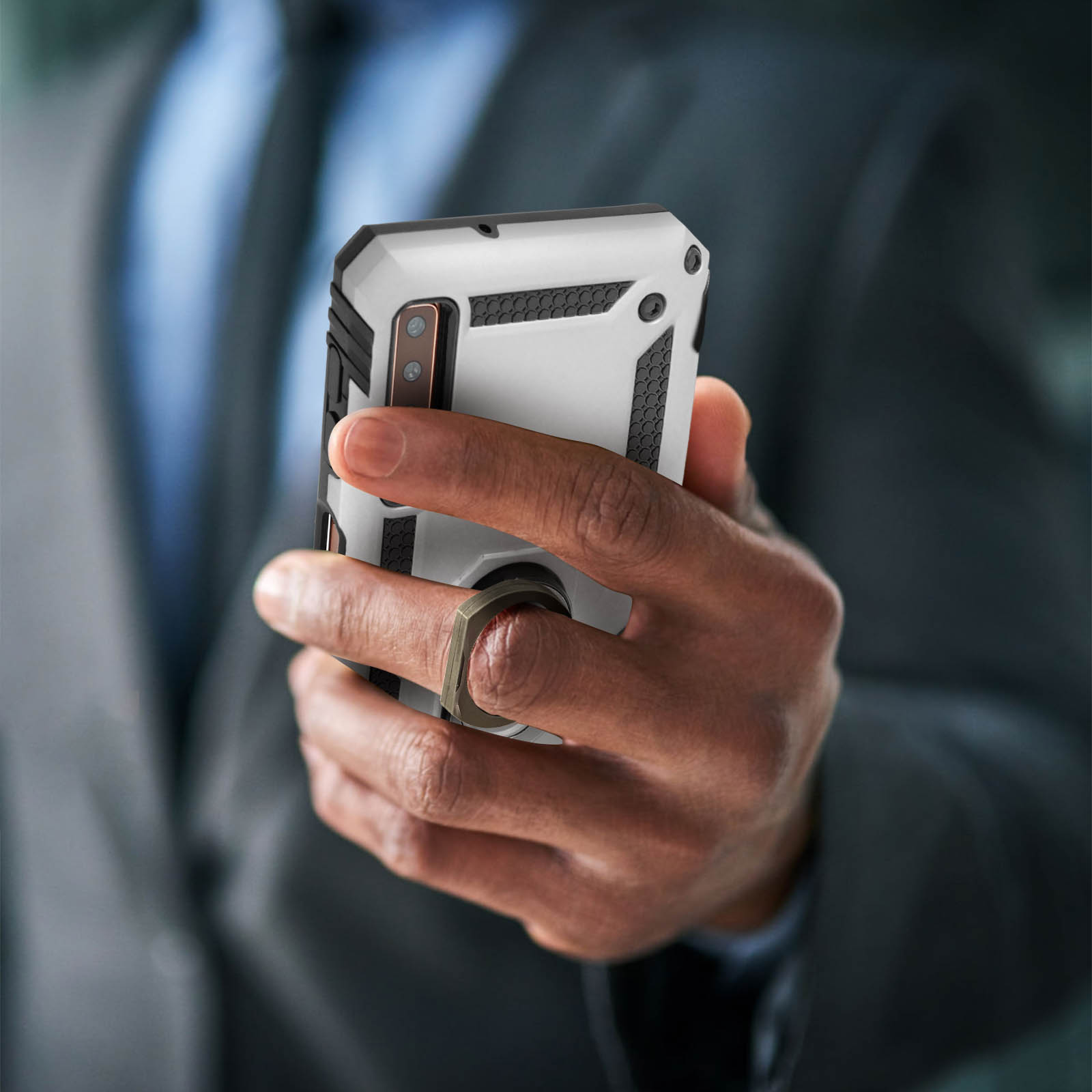 Eine Hand, die ein weißes und schwarzes Telefon in einem Anzug hält. Das Telefon hat einen Ring.