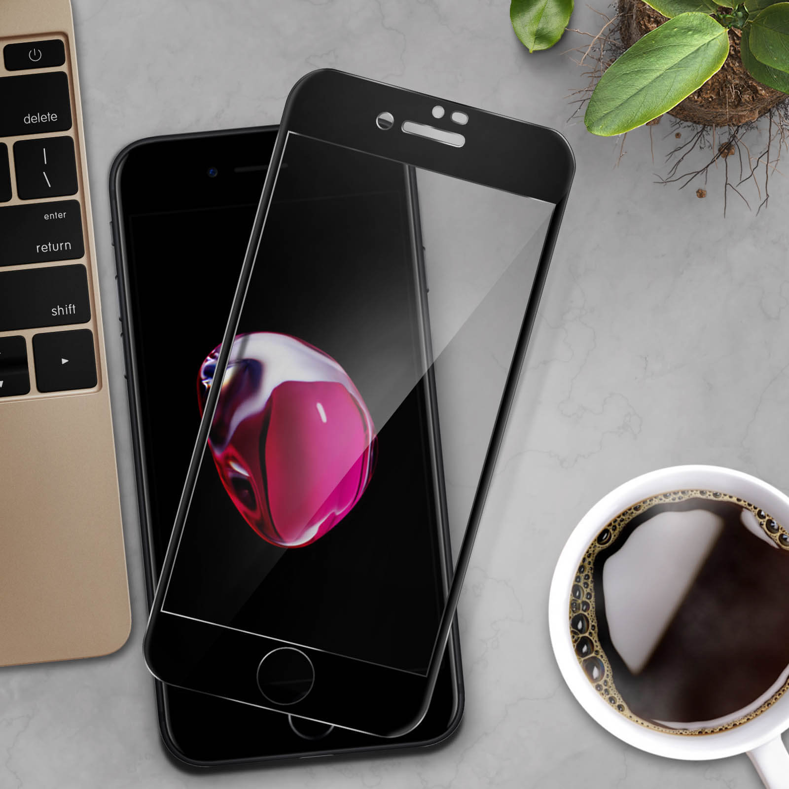 Telefono nero con protezione schermo, tastiera, tazza di caffè e pianta su una scrivania.