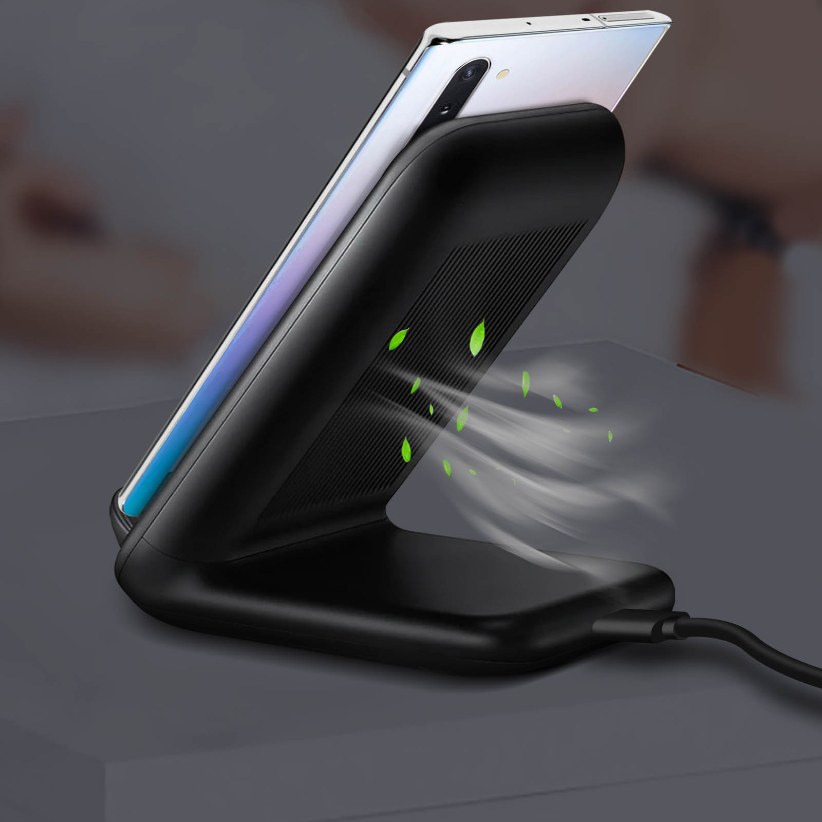 Un cargador inalámbrico negro con un teléfono encima. Hojas verdes se visualizan como flujo de aire.