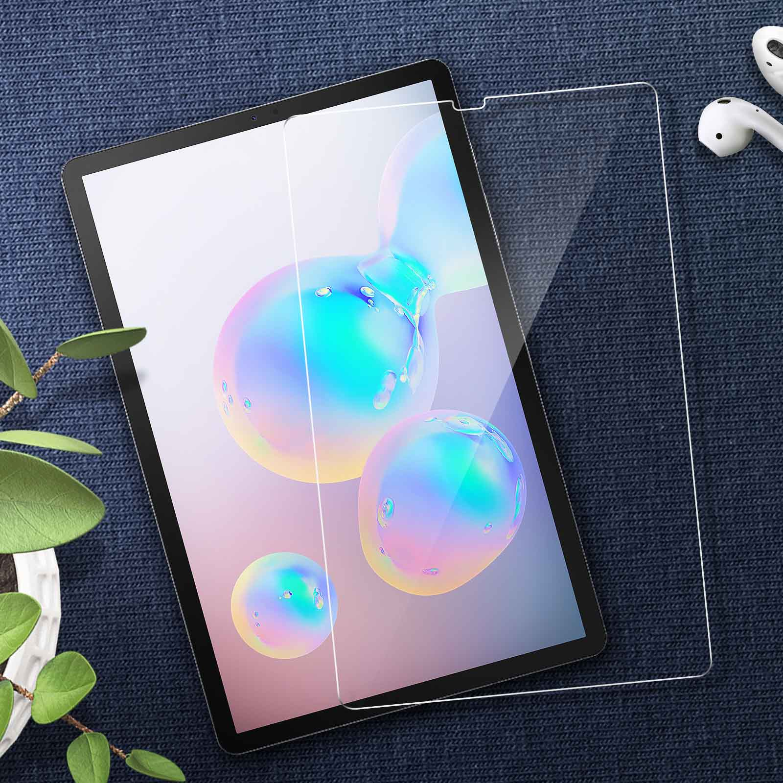 Un tablet con un proteggi schermo in fase di applicazione. Il tavolo ha una superficie blu e ci sono auricolari nelle vicinanze.