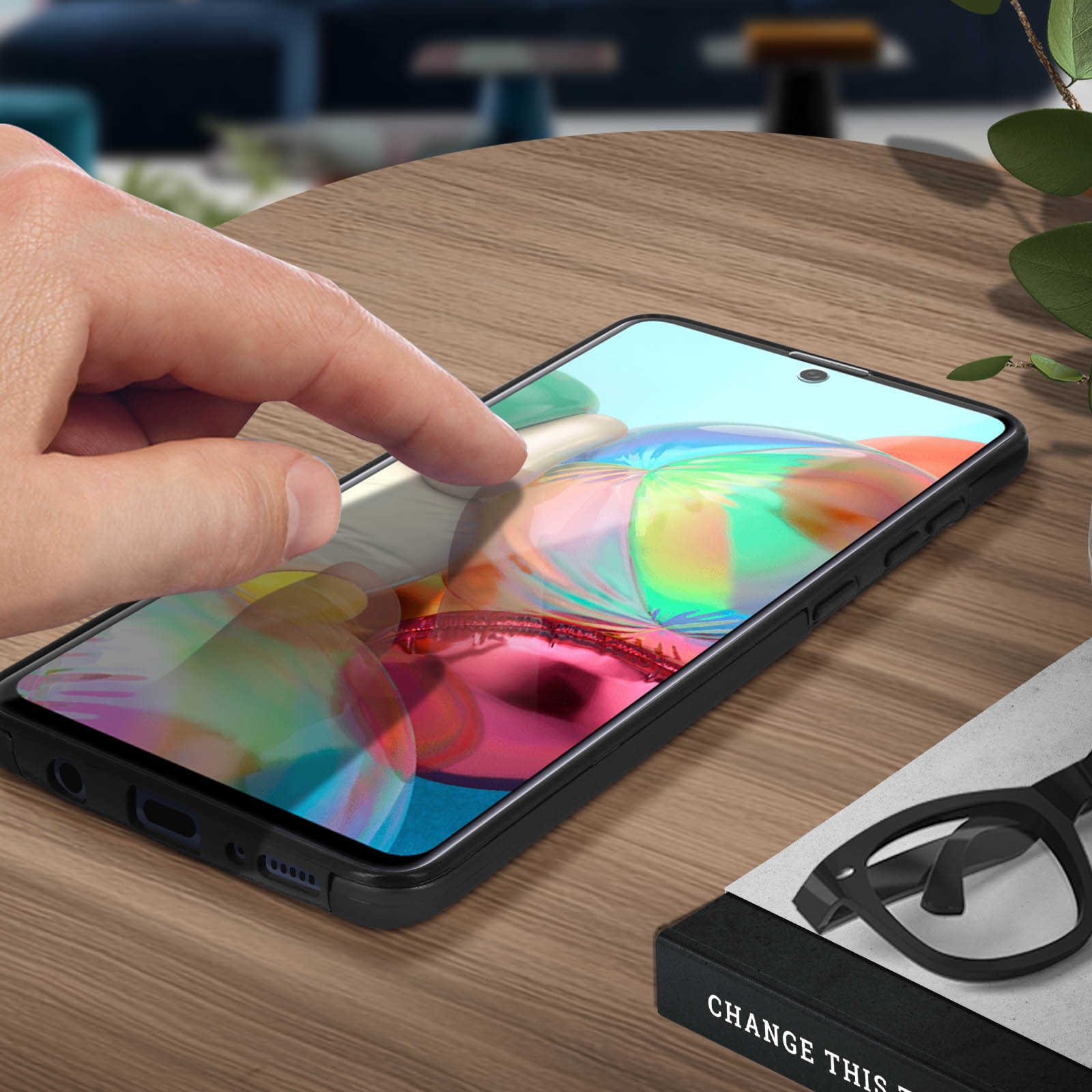 Une main touche l'écran du téléphone. Lunettes et un livre à côté du téléphone.