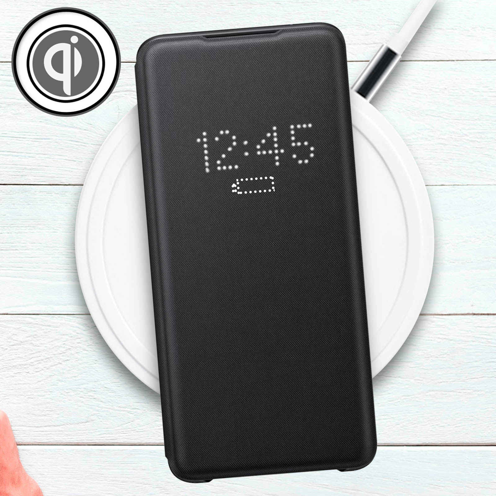 Teléfono negro en funda negra sobre cargador inalámbrico blanco. Pantalla muestra hora. Símbolo Qi a la izquierda.