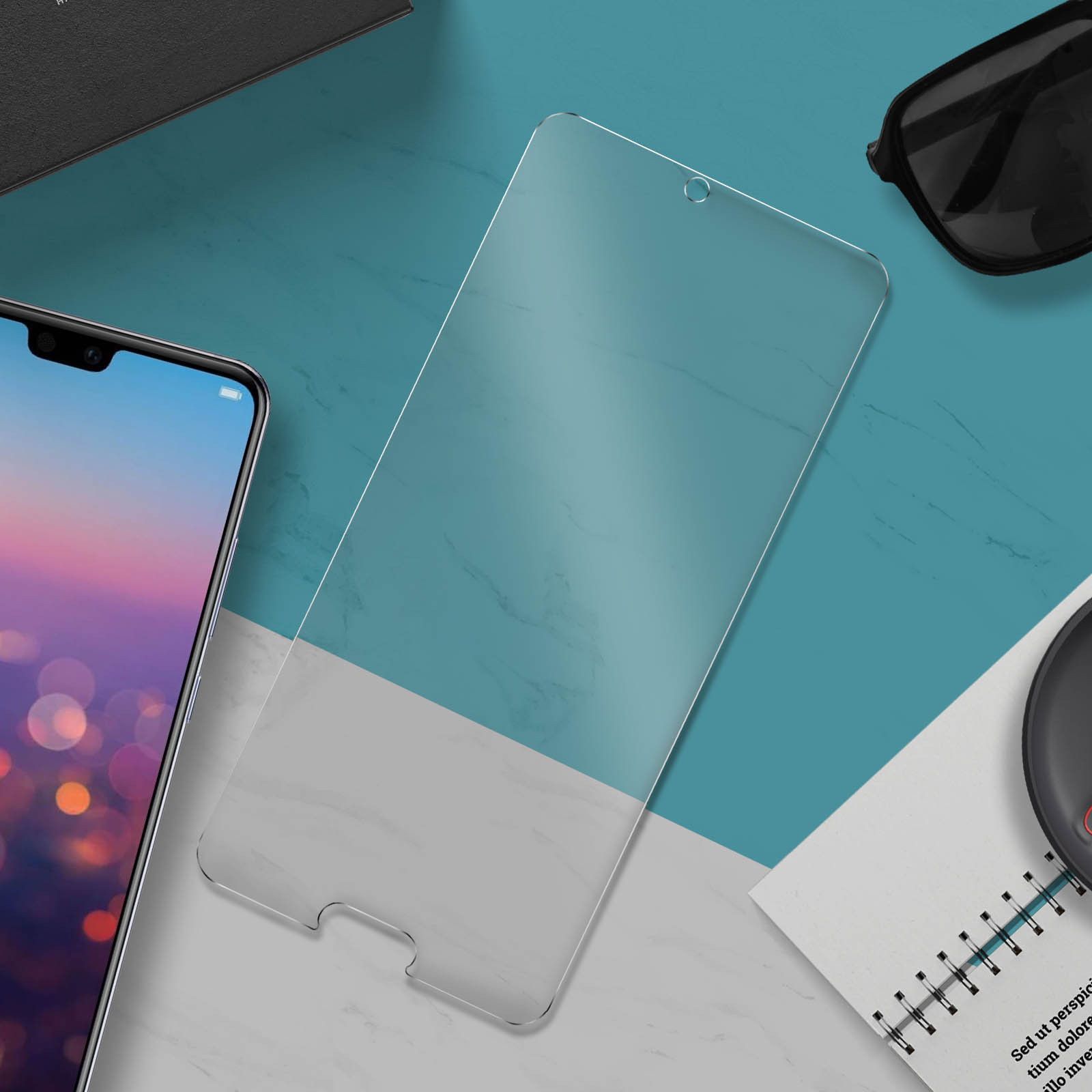 Protezione schermo su una superficie con taccuino, occhiali da sole e telefono.