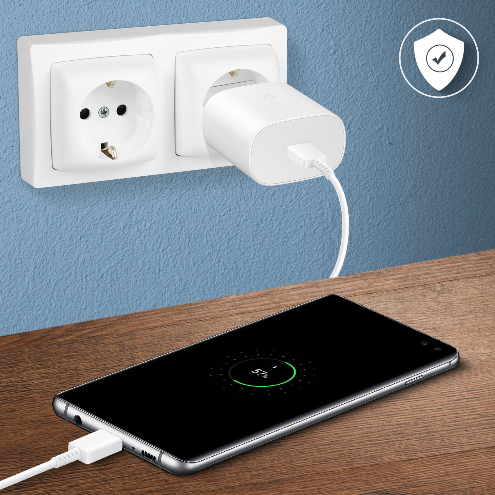 Un téléphone en charge à côté d'une prise murale. Le téléphone affiche 57% de charge.