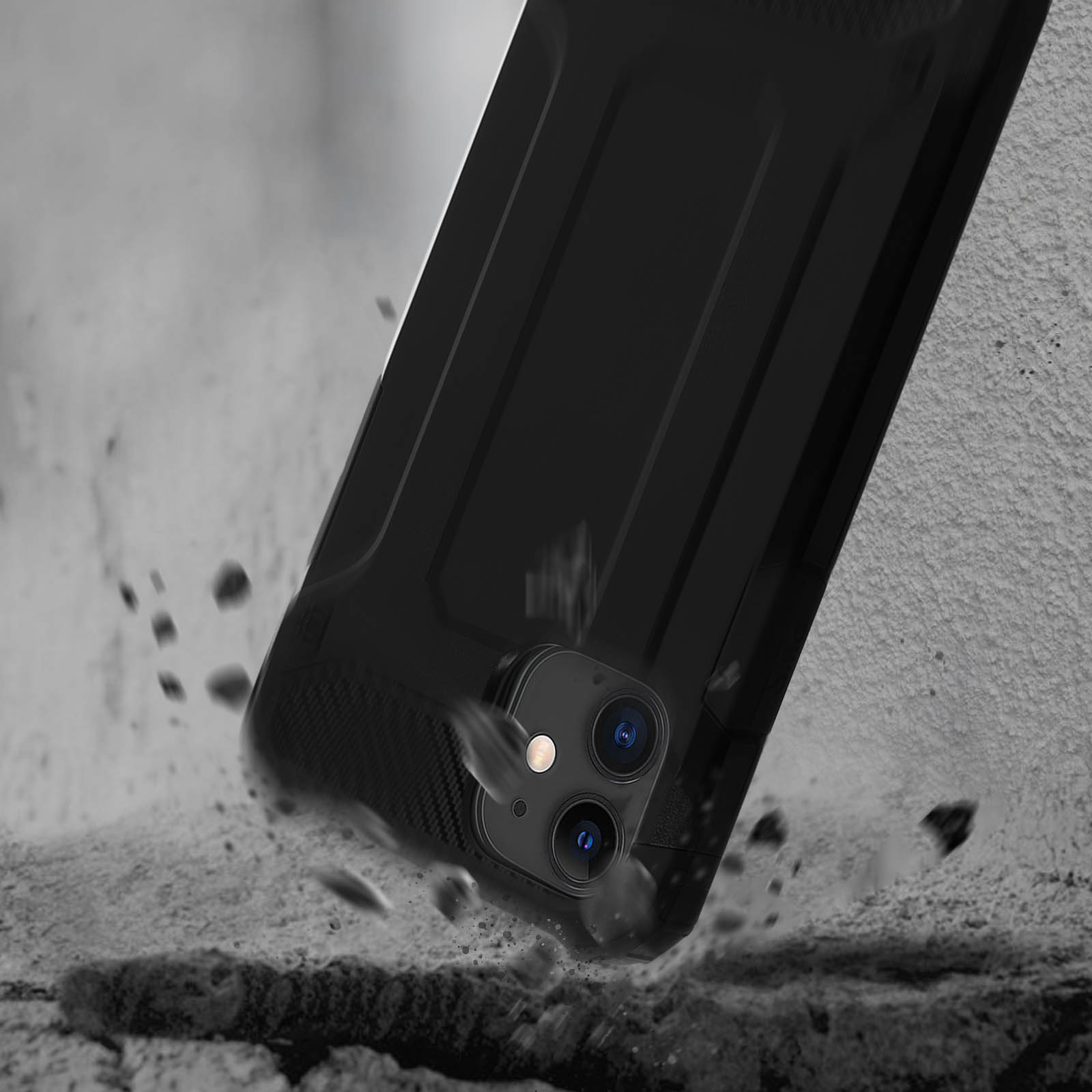 Custodia nera che cade, fotocamera del telefono visibile. Detriti e superficie strutturata sullo sfondo.