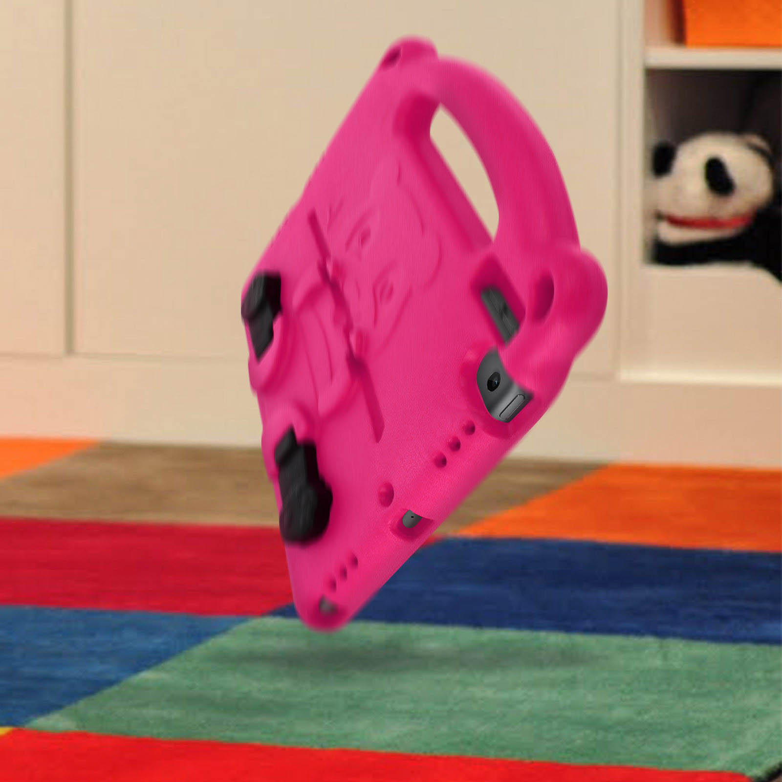 Rosa Tablethülle mit Griff und schwarzen Knöpfen. Auf einem bunten Teppich platziert.