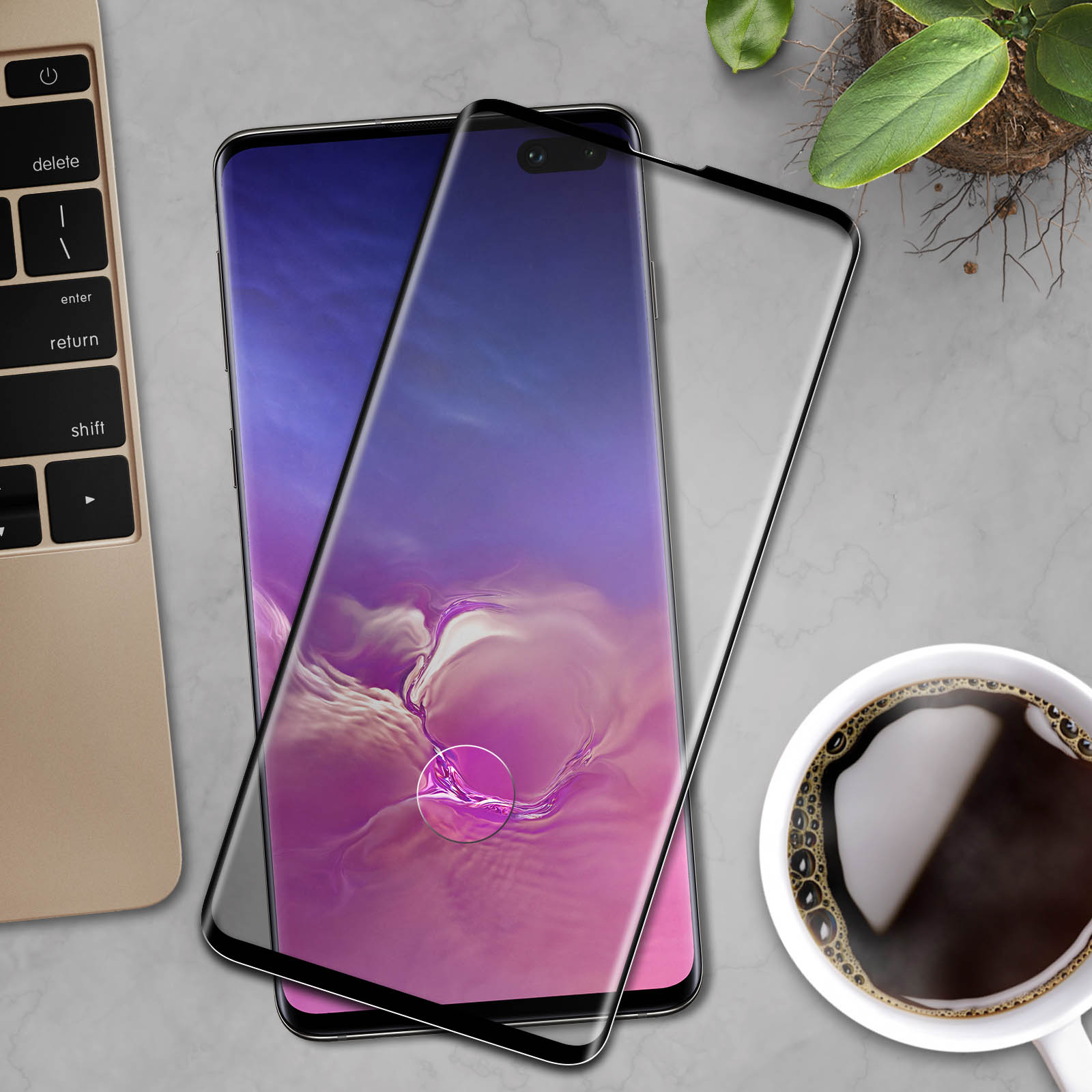 Telefono con protezione schermo, laptop, caffè e una pianta su una superficie.