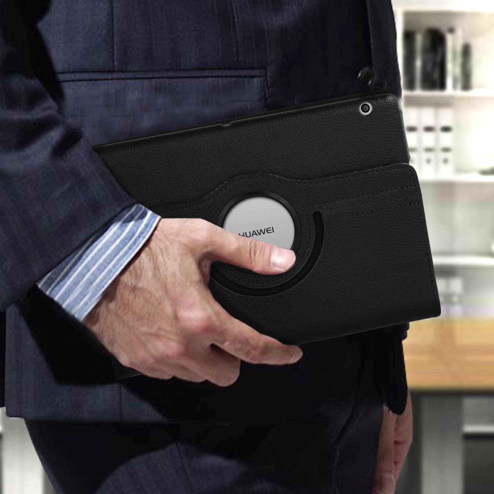 Persona che tiene un tablet nero in una custodia nera. Sfondo: scena d'ufficio.