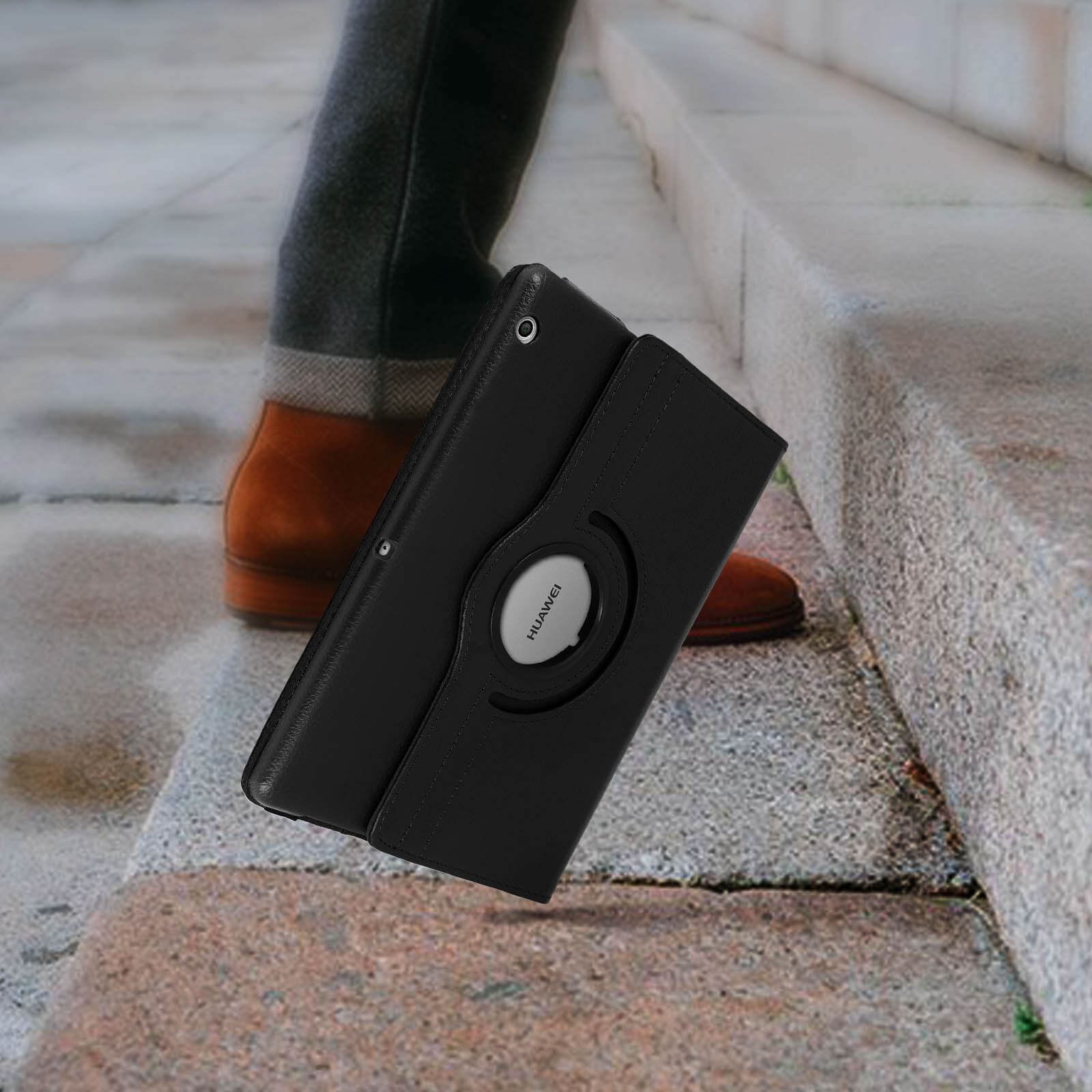 Una custodia nera per tablet, in posizione aperta, su un gradino, con una persona che cammina.