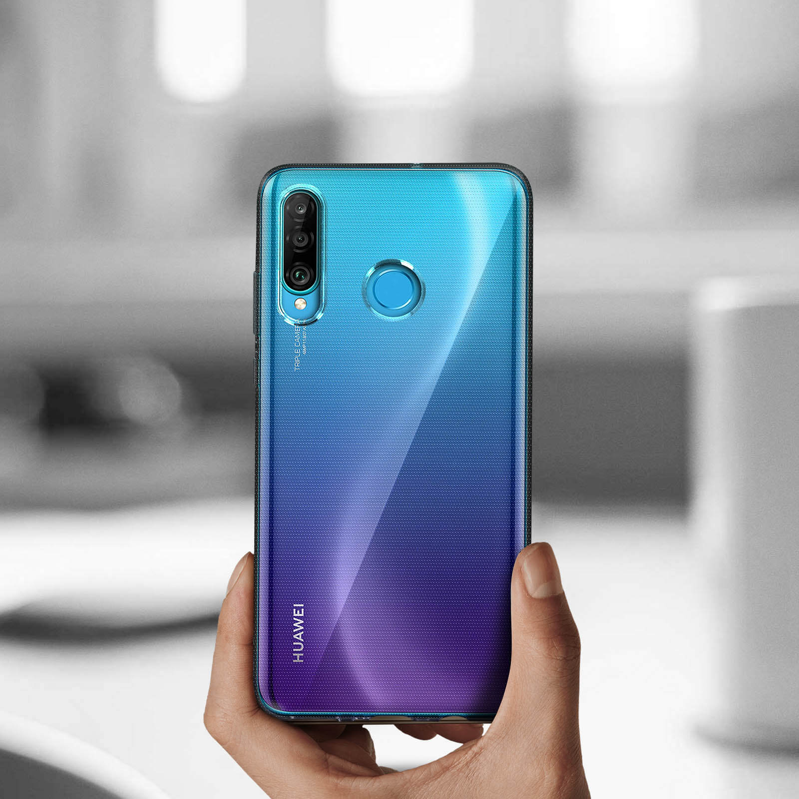 Hand hält ein blau-lila Farbverlaufstelefon, dunkler verschwommener Hintergrund.