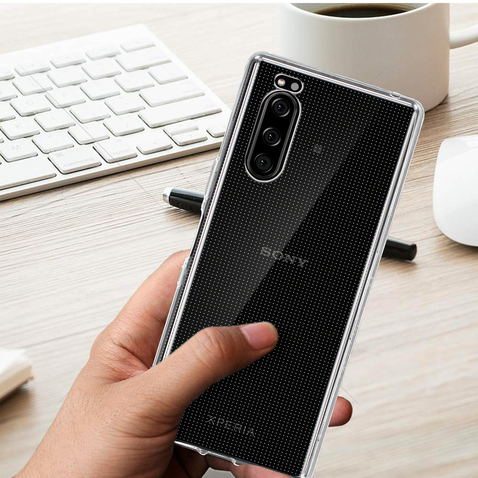 Una custodia trasparente per telefono con un design a pois neri. Il telefono è su una tastiera e una tazza.
