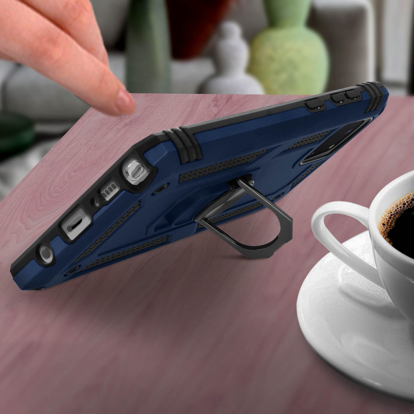 Una custodia blu per telefono con un supporto. Il telefono è su una superficie di legno con una tazza di caffè.
