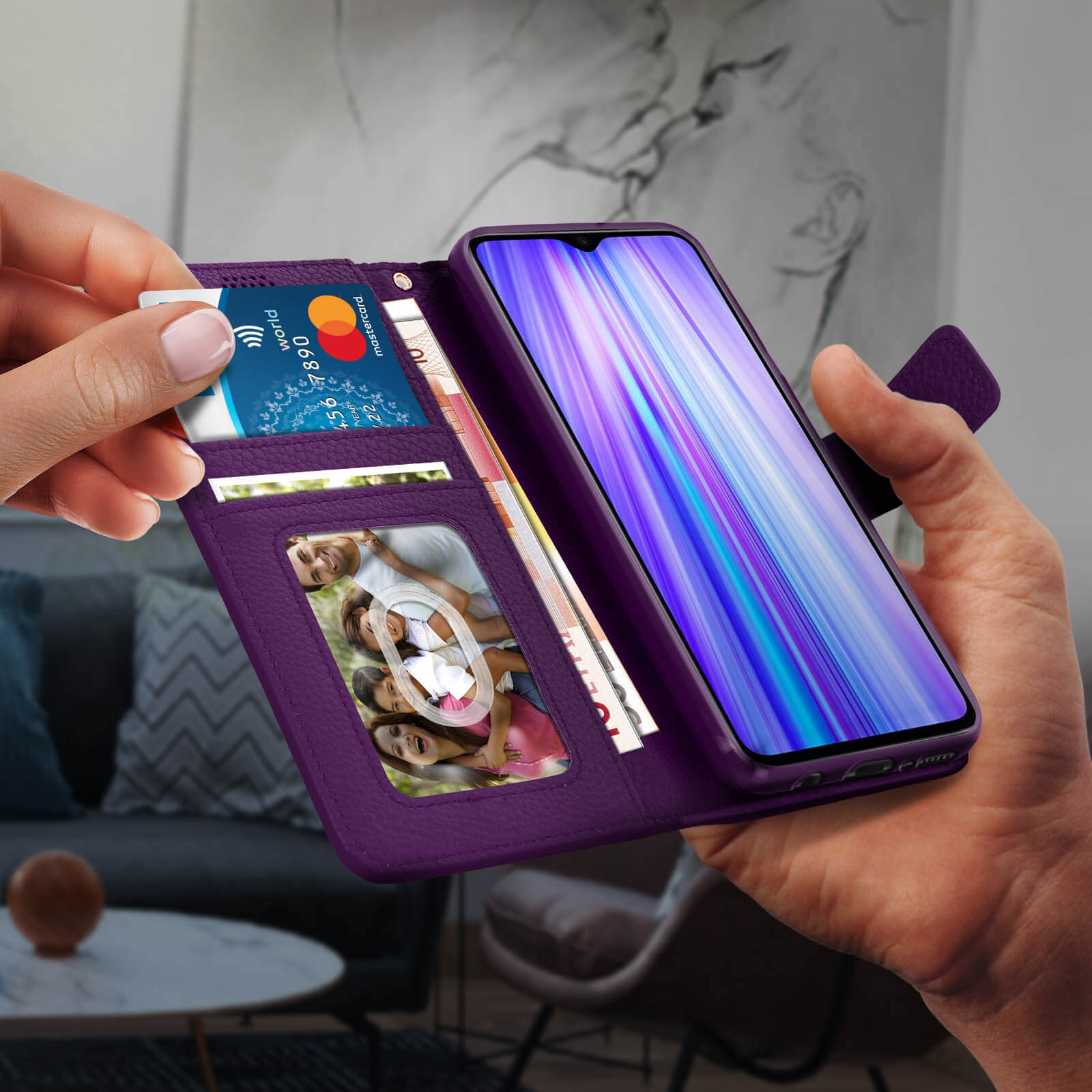 Een paarse telefoonhoes met een telefoon, creditcards en contant geld. Een hand steekt een kaart in.