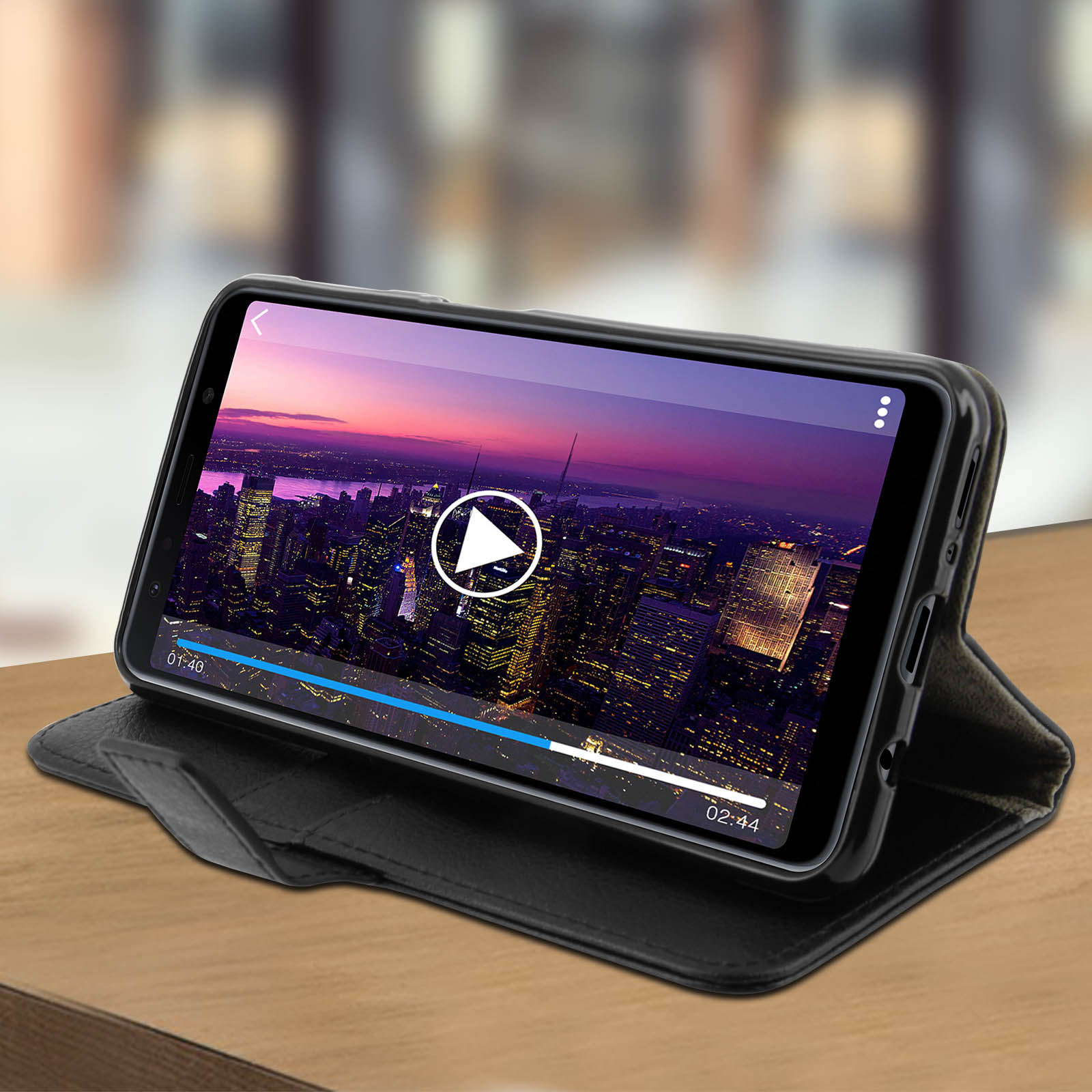 Un telefono nero in una custodia a libro mostra un video. Lo schermo mostra una città di notte e un pulsante di riproduzione.