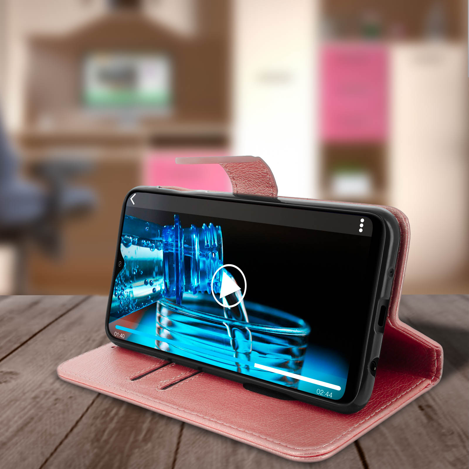Een telefoon in een roze hoes speelt een video af met een afspeelknop op een houten bureau.