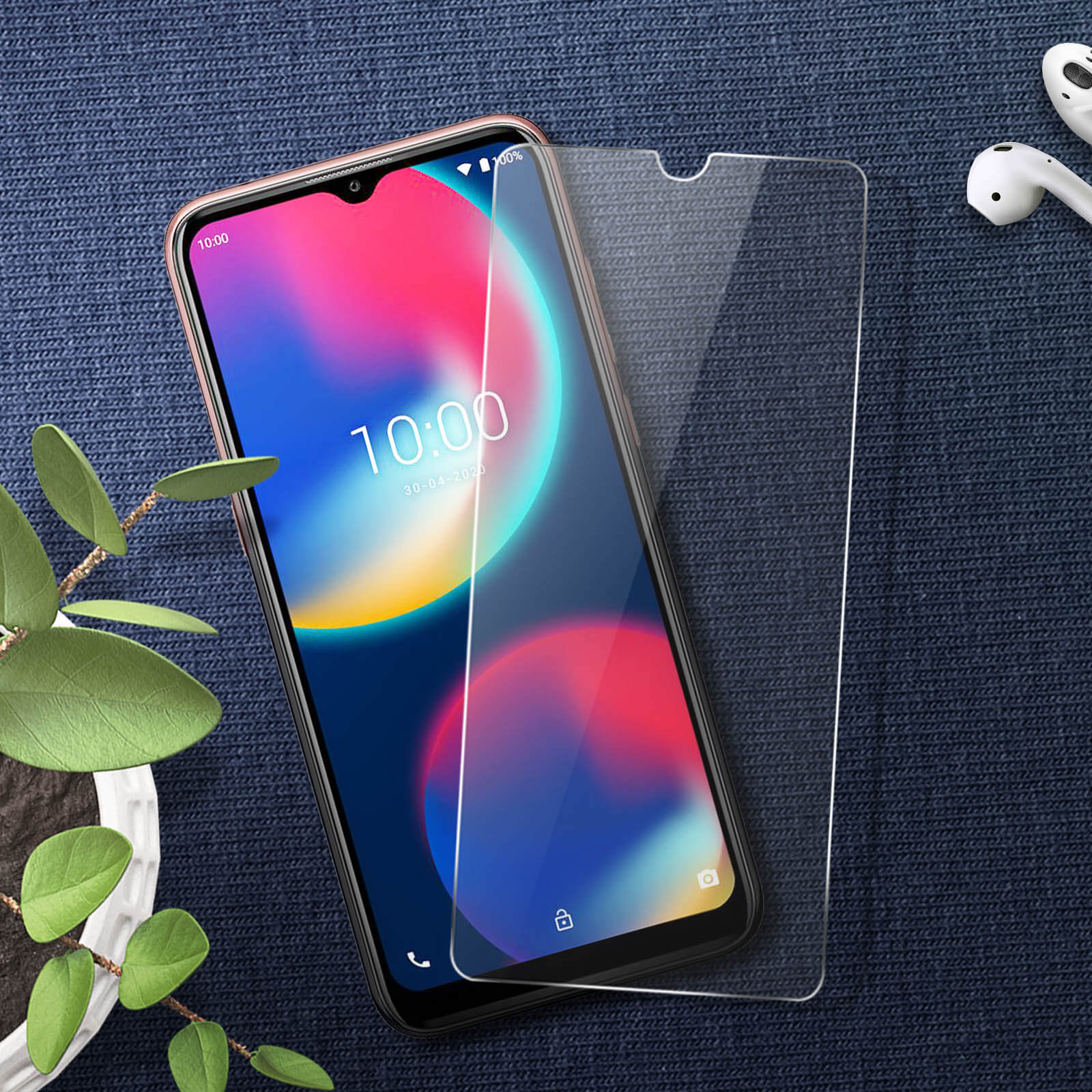 Telefoon met schermbeschermer. De telefoon staat op een blauw oppervlak. Oordopjes zijn zichtbaar.