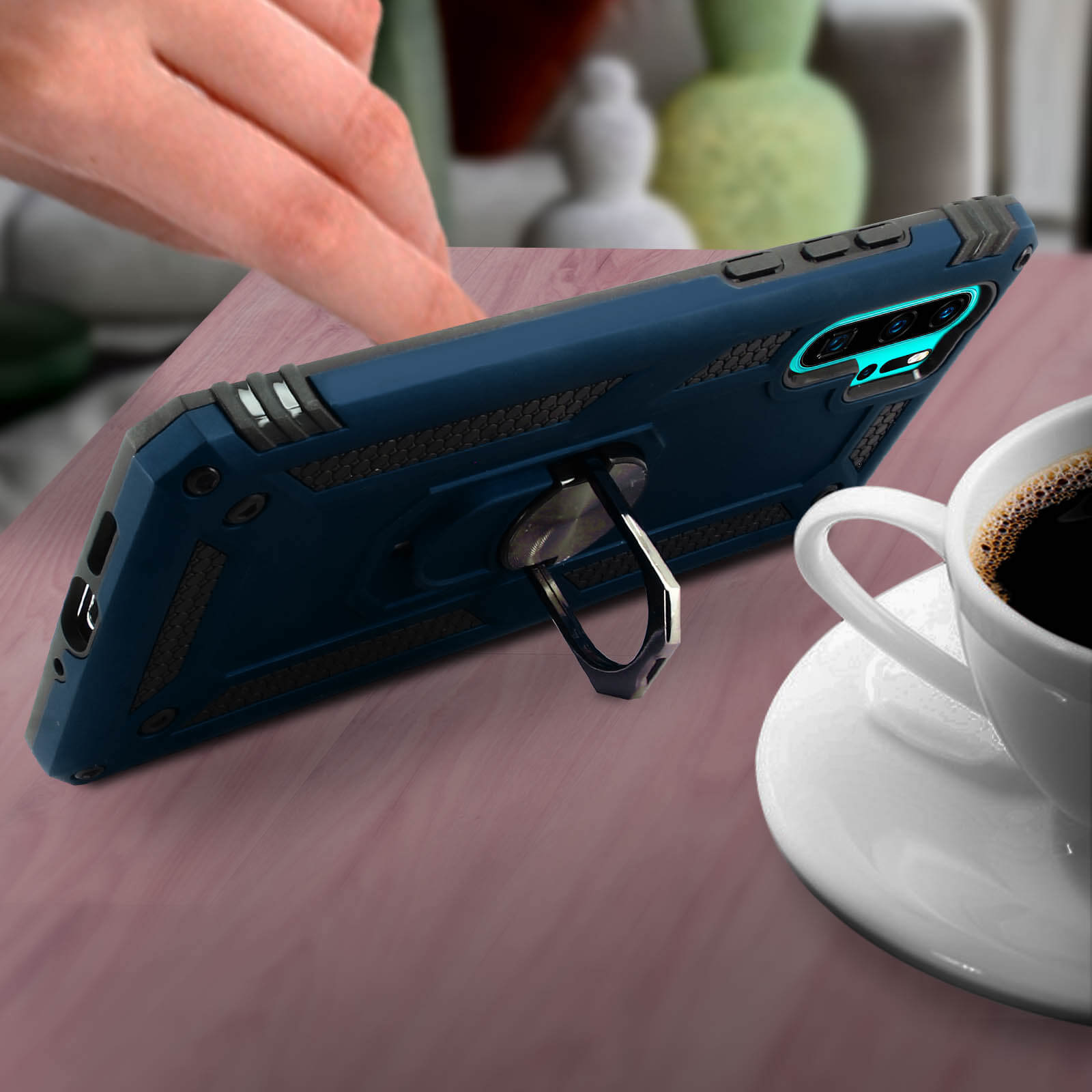 Custodia blu con anello, tazza di caffè e pianta. Tavolo di legno. Sfondo sfocato.