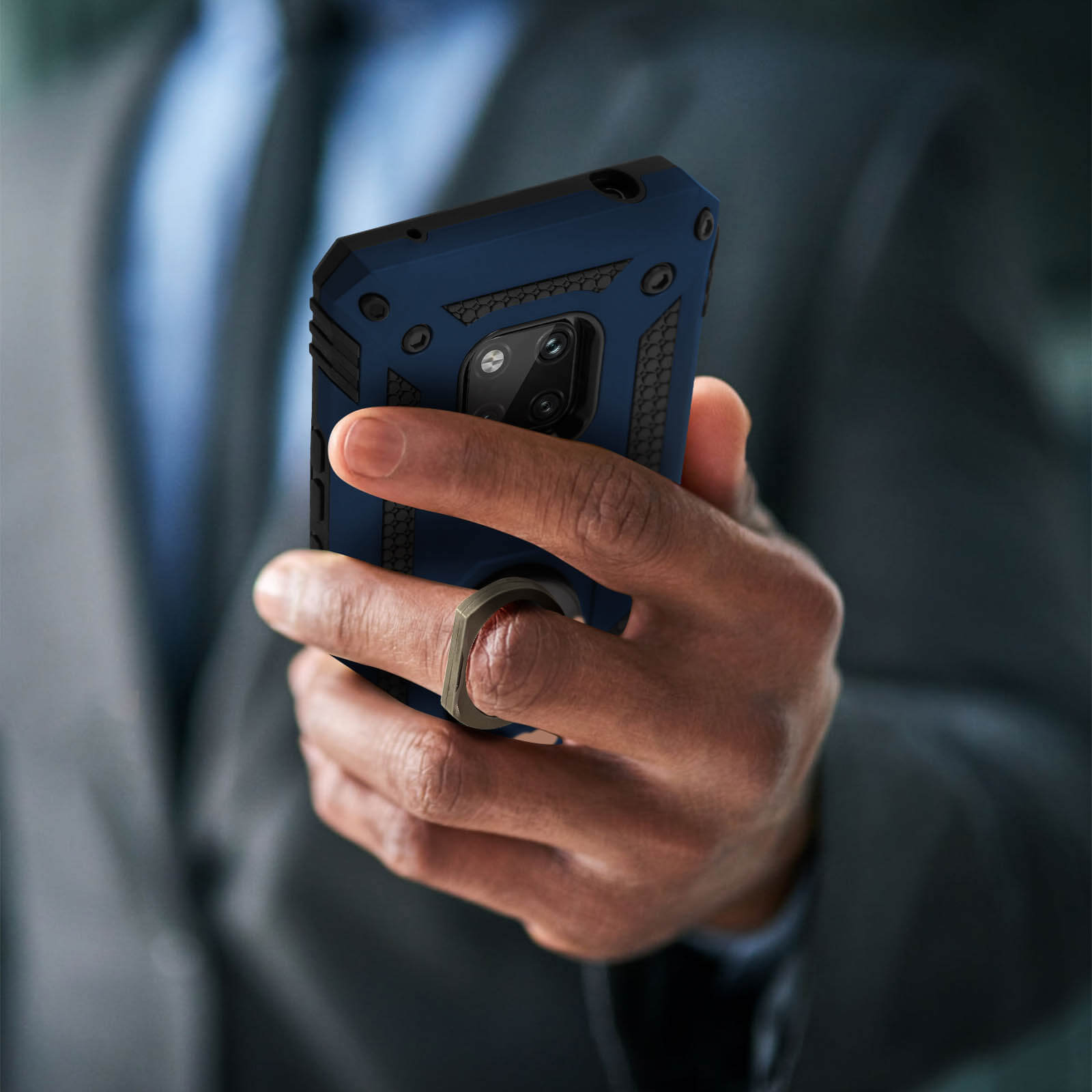 Een persoon houdt een telefoon vast in een donkerblauwe hoes met ringhouder. De achtergrond is vaag.