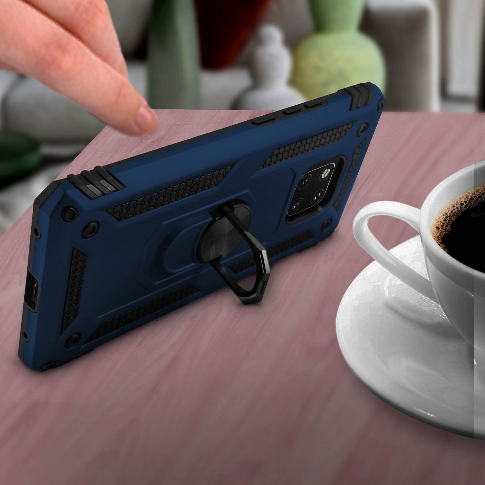Telefoon in blauwe hoes met ringhouder, naast een kopje koffie.