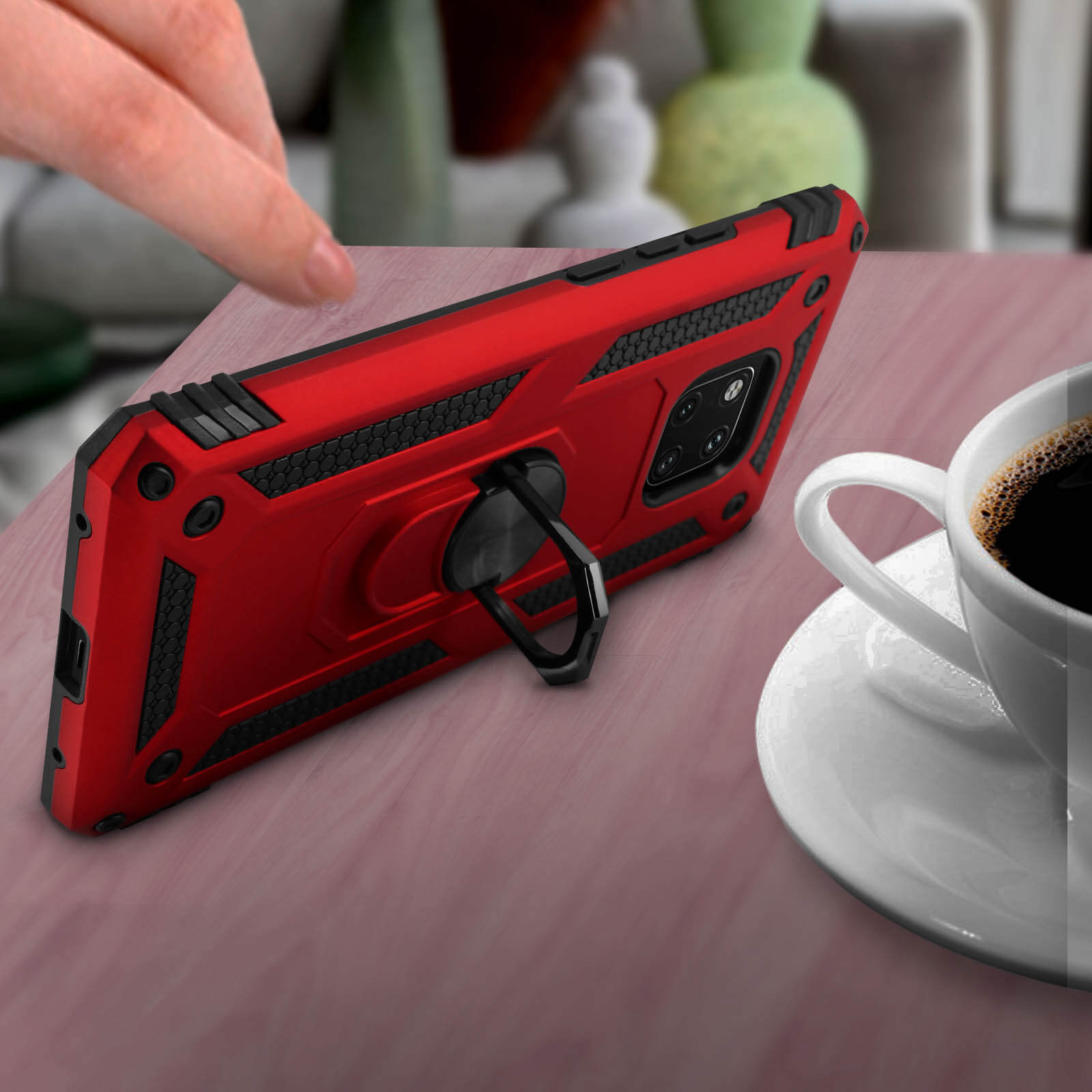 Une coque de téléphone rouge avec un support d'anneau, sur une table. Une tasse de café est en arrière-plan.