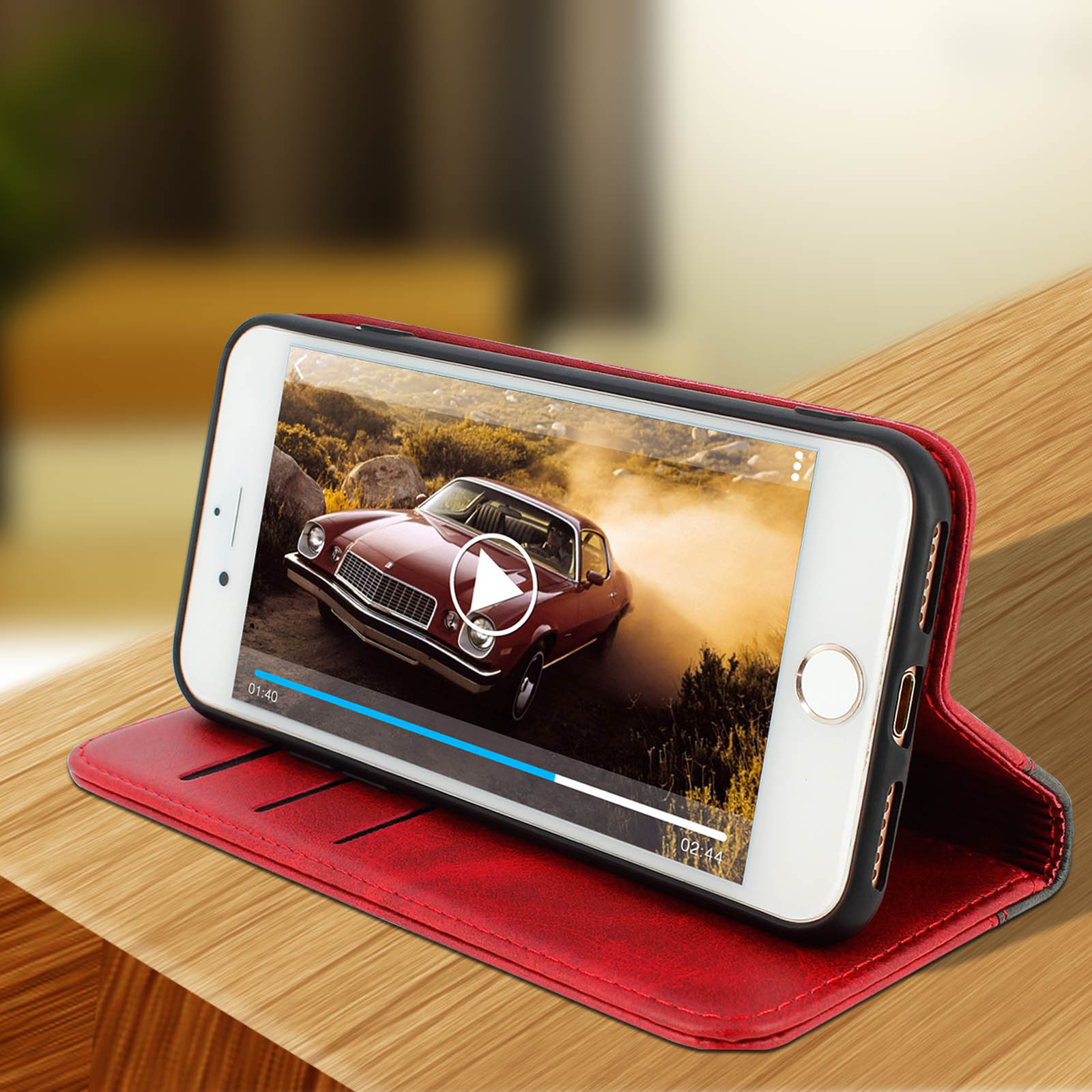 Un telefono è su una superficie di legno, mostra un video. Una custodia rossa è sul retro.